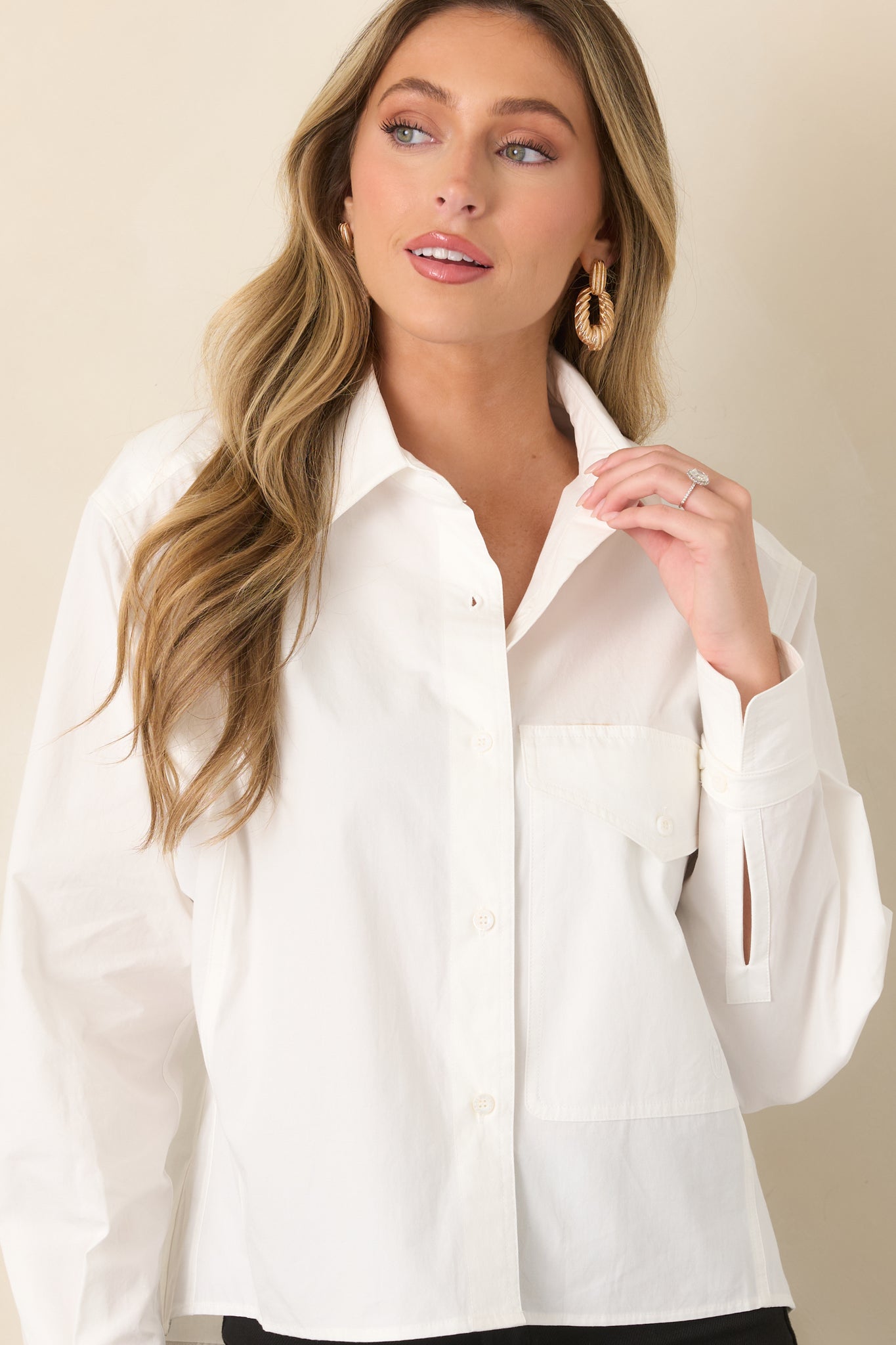 Relaxed button-front top featuring a pointed collar, oversized flap chest pocket, long sleeves with wide cuffs, and an easy refined silhouette.