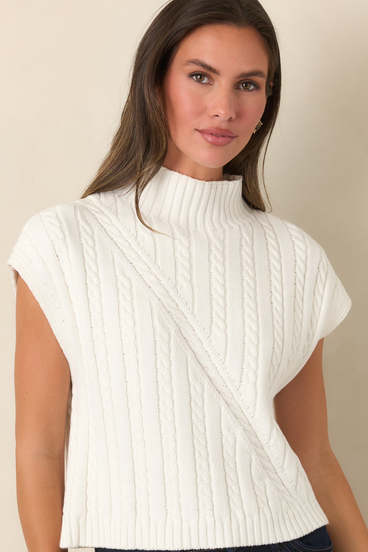 Relaxed ivory sweater showcases dimensional cable-knit texture and a clean mock neckline with ribbed edging.