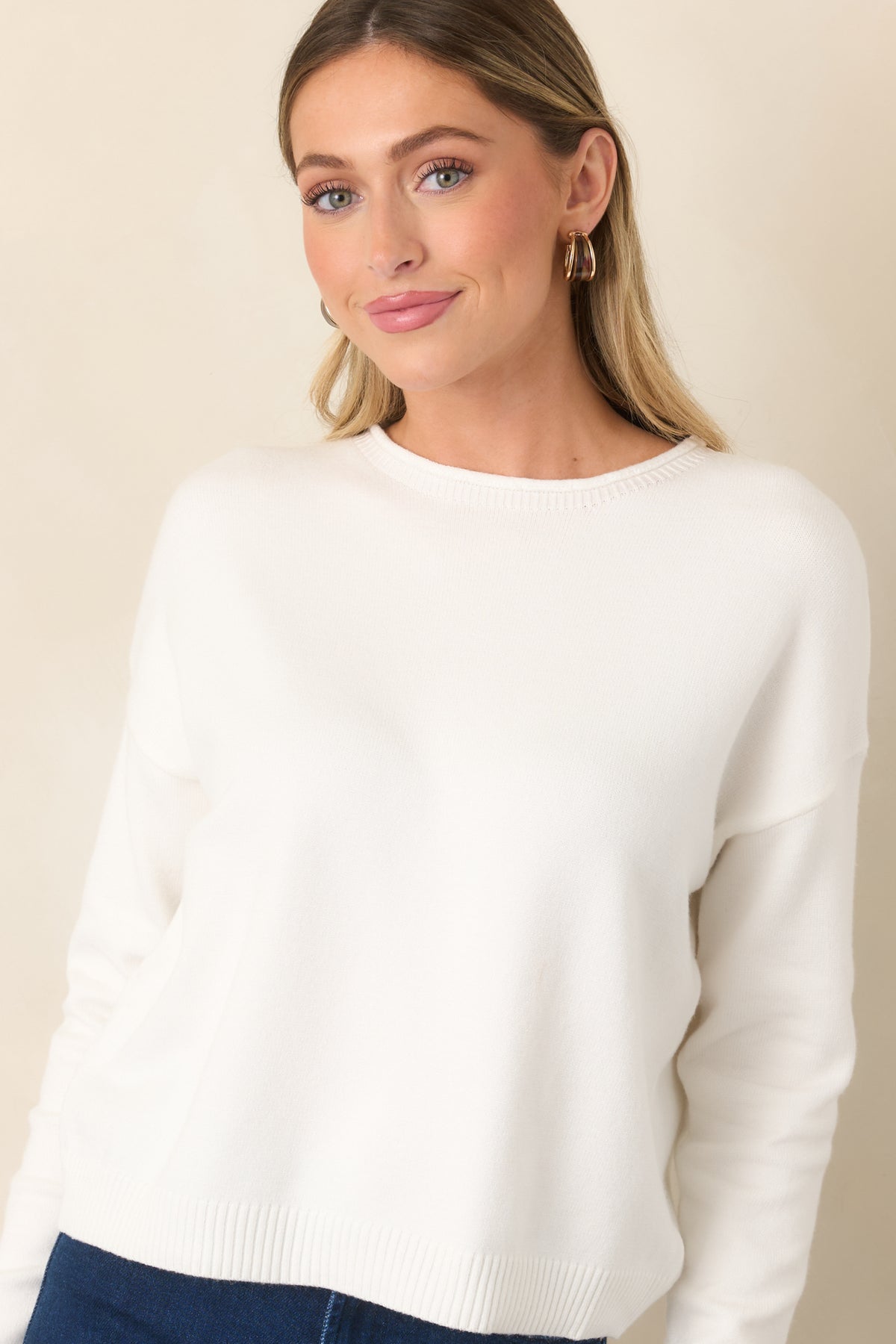 Relaxed ivory top features dropped shoulders flowing into long sleeves with ribbed cuffs.