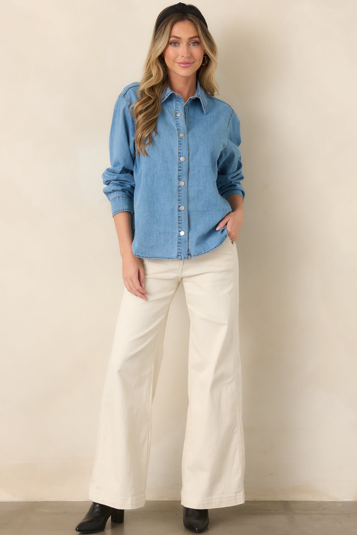 Relaxed light wash cotton top featuring a classic collar, button-front design, rolled sleeves, and an easy curved hemline.
