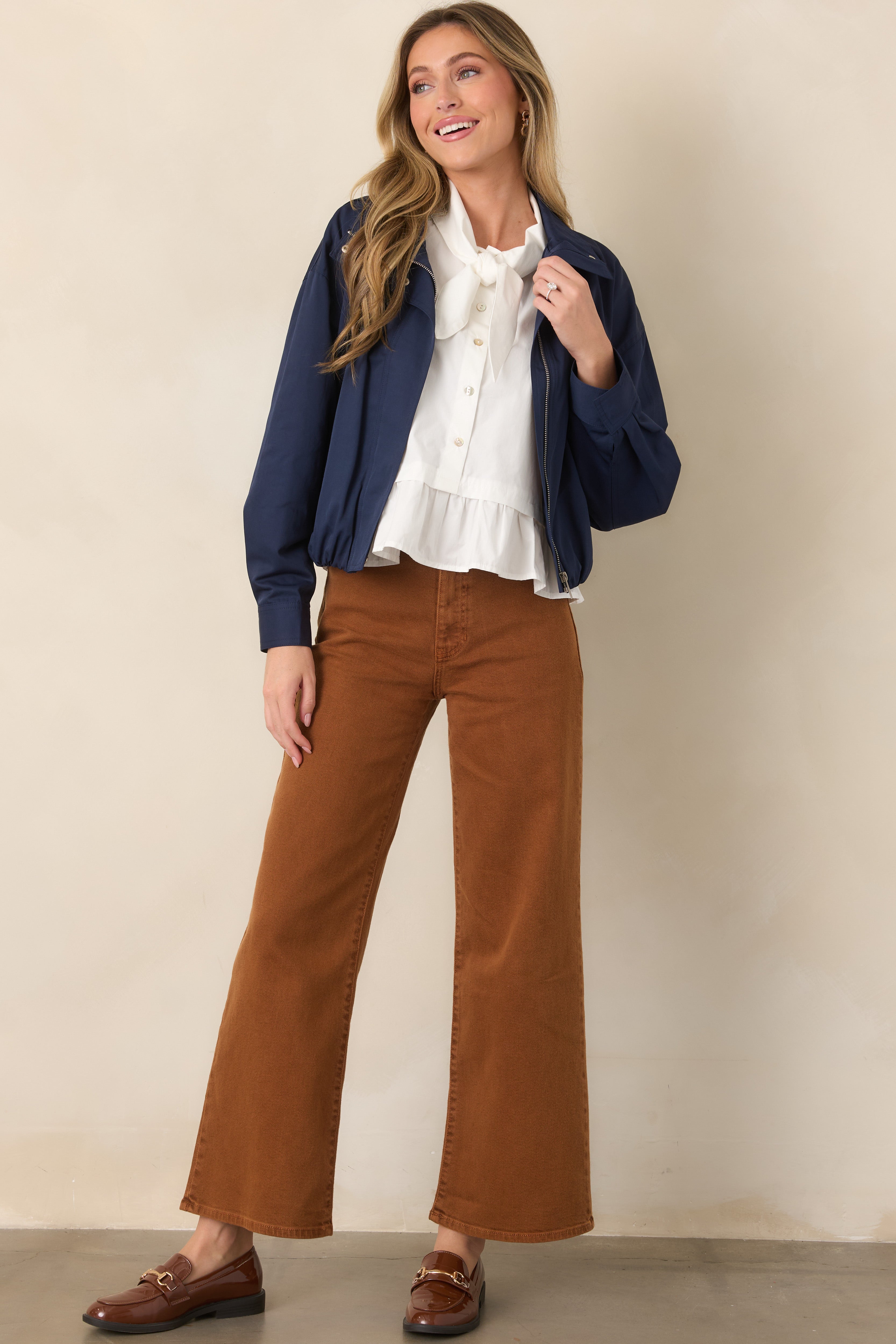 Relaxed navy bomber jacket featuring long sleeves, button cuffs, functional welt pockets, and an elasticized hem for a defined shape.