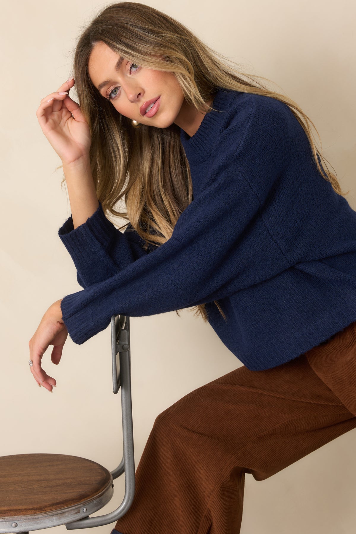 Relaxed navy knit pullover with dropped shoulders, long sleeves, and ribbed cuffs creating a clean finish.
