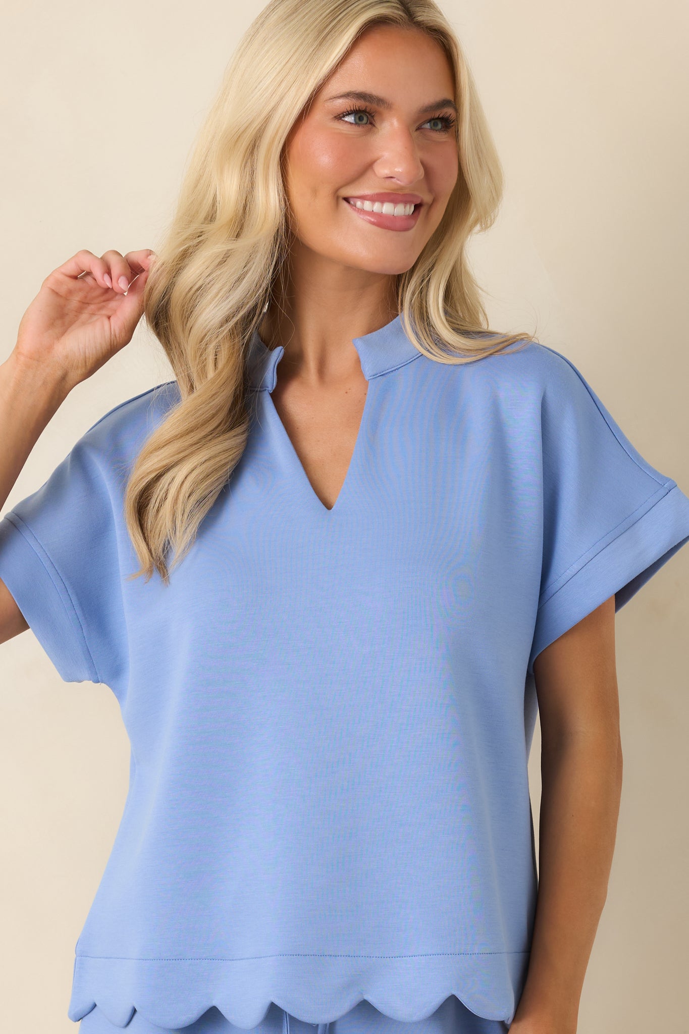 Relaxed pullover top highlighting the modern neckline and polished sleeve accents.
