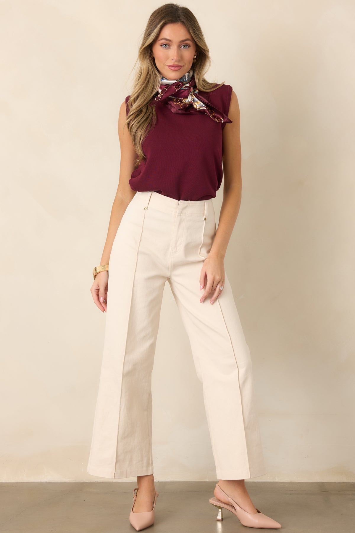 Relaxed sweater knit top highlighting its smooth texture, sleeveless design, crew neckline, and modern row of gold-tone side buttons.
