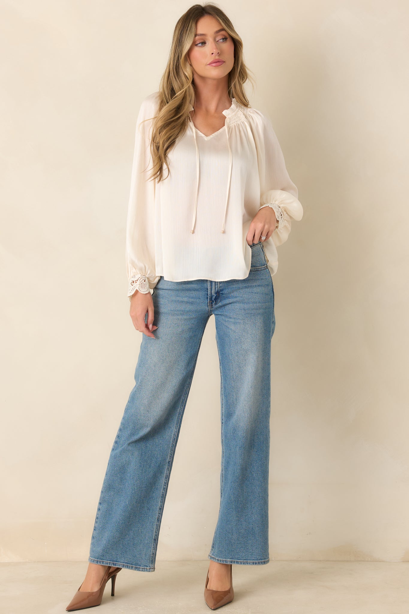 Relaxed textured blouse featuring a smocked ruffle neckline, a split V-shaped opening with slender gold-tone tipped ties, voluminous balloon sleeves, and intricate lace cuffs for an elegant finish.