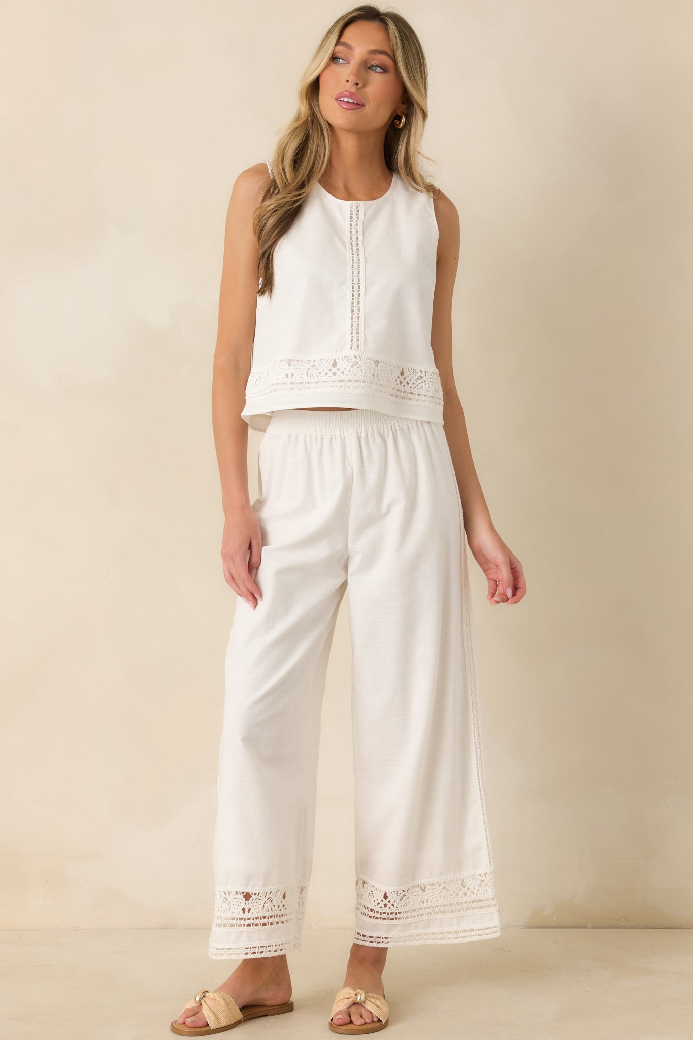 Relaxed white pants showcasing a flowing wide-leg silhouette, side pockets, and intricate embroidered lace accents for a soft, airy look.
