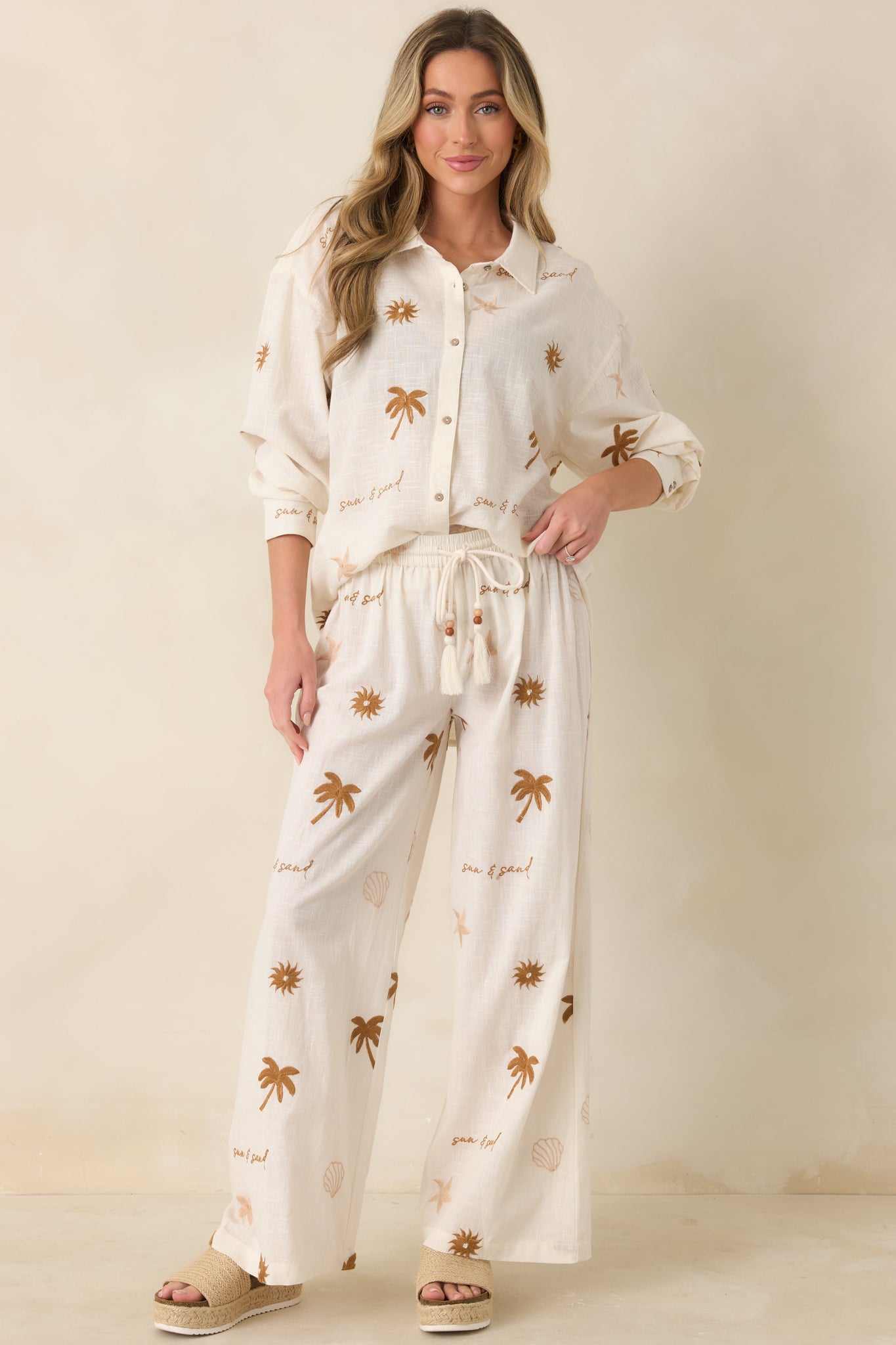 Relaxed wide-leg pants in beige with adjustable drawstring and bead accents.