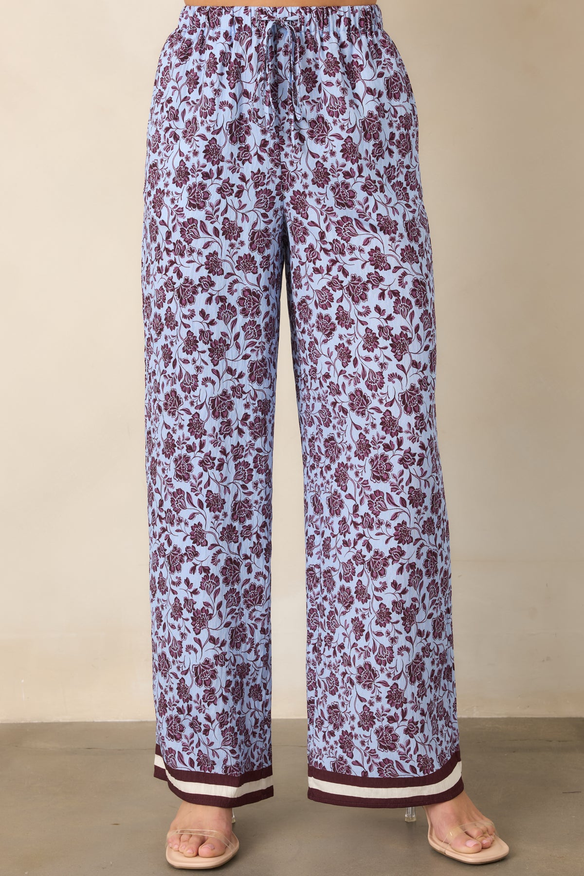 Relaxed wide legs display the burgundy floral pattern against pale lilac with distinctive striped hem accents.