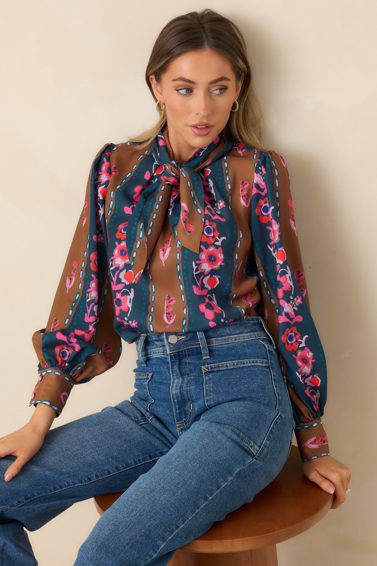 Removable neck tie arranged in a bow above the deep blue and caramel floral stripe print.