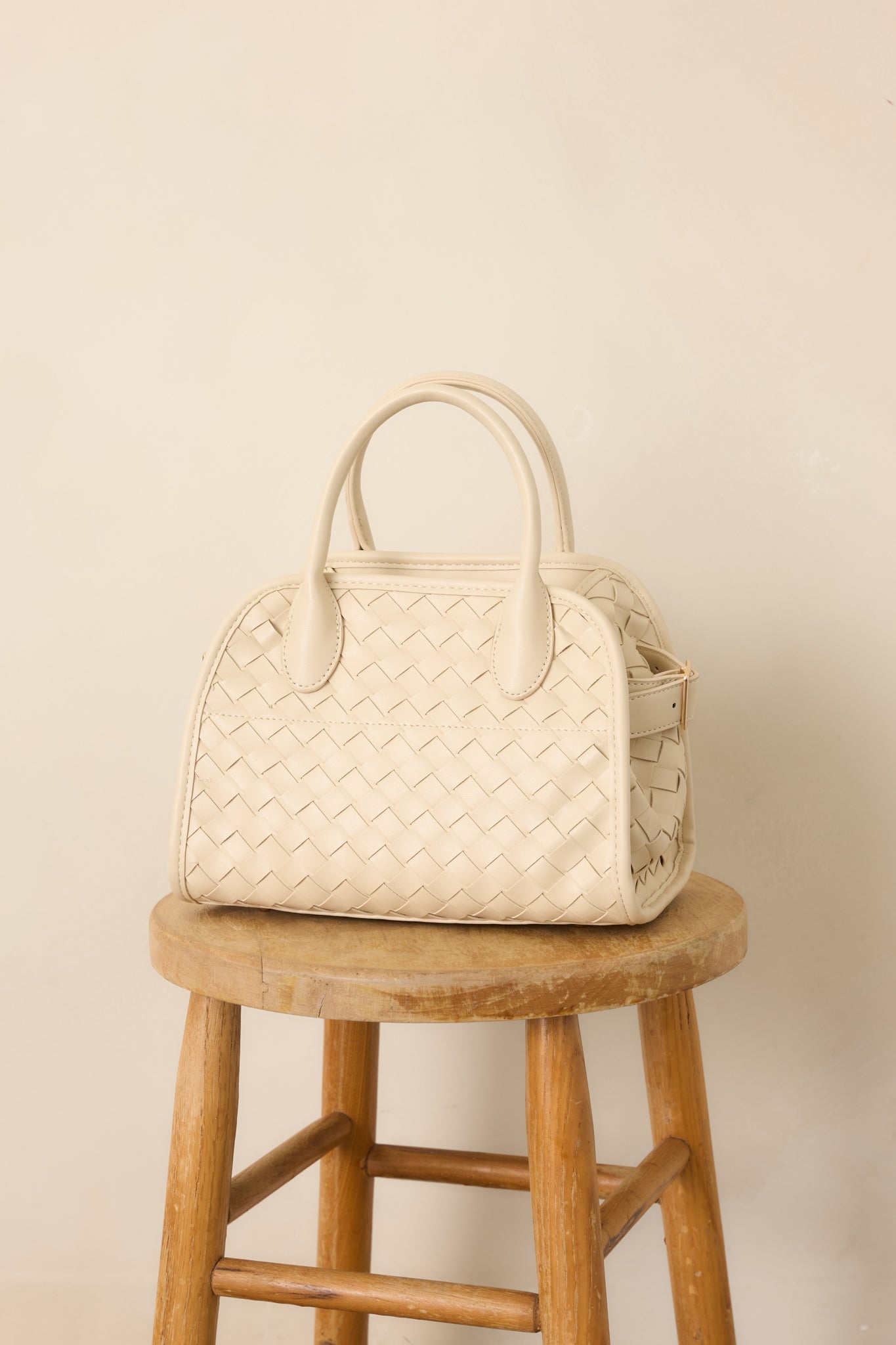Detailed view of the handbag's removable crossbody strap, top handle, and clean structured silhouette.