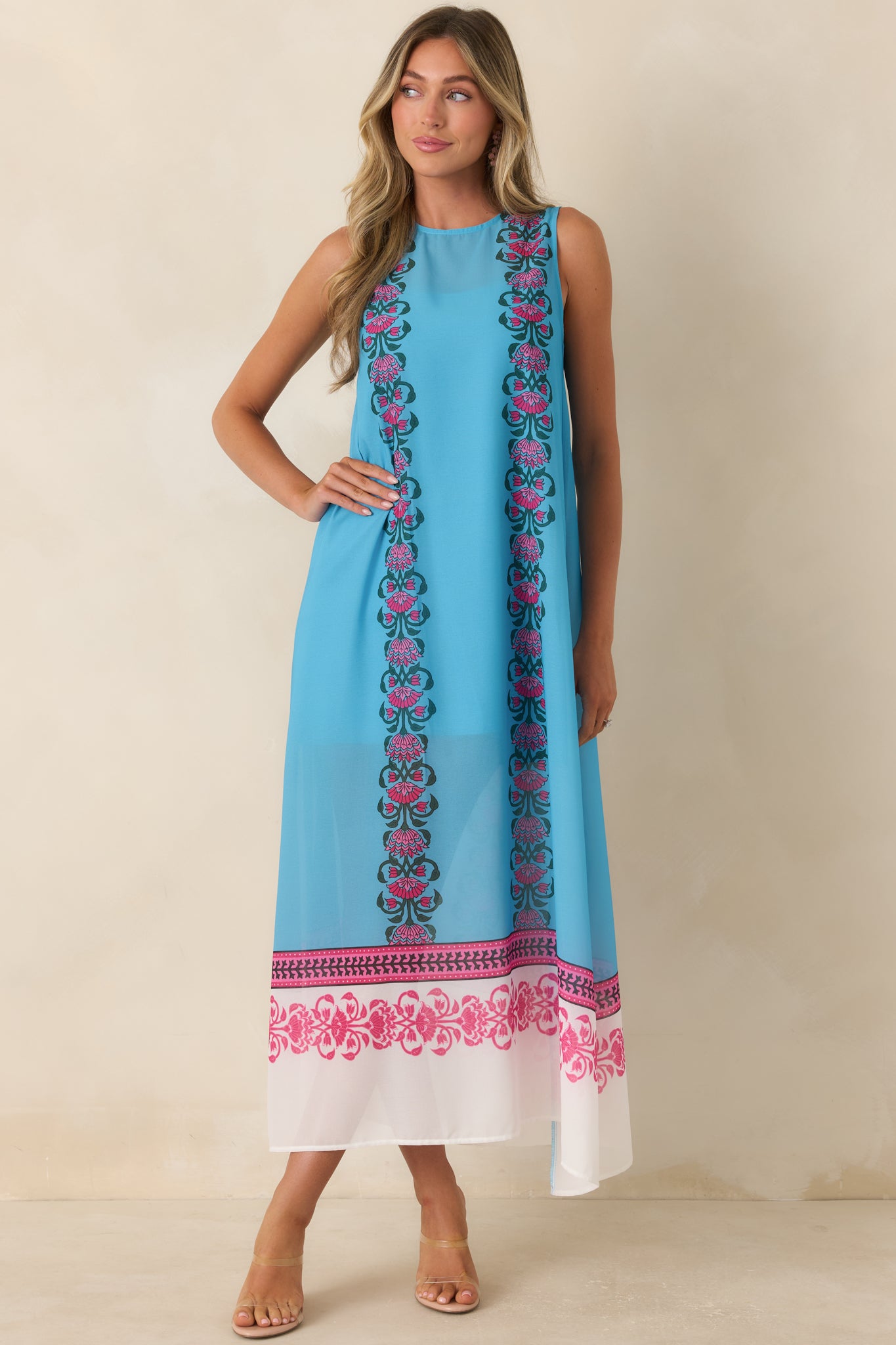 Resort-style blue maxi dress crafted from airy fabric and finished with vivid floral border prints for an elegant, flowing appearance.