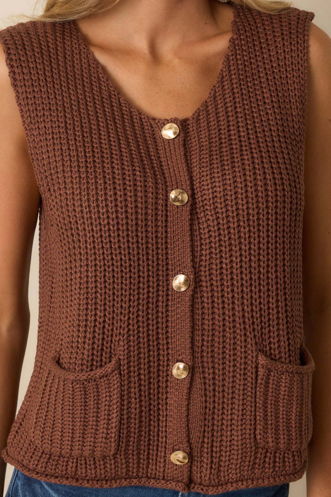 Detailed shot of the ribbed knit fabric and gold button front closure.