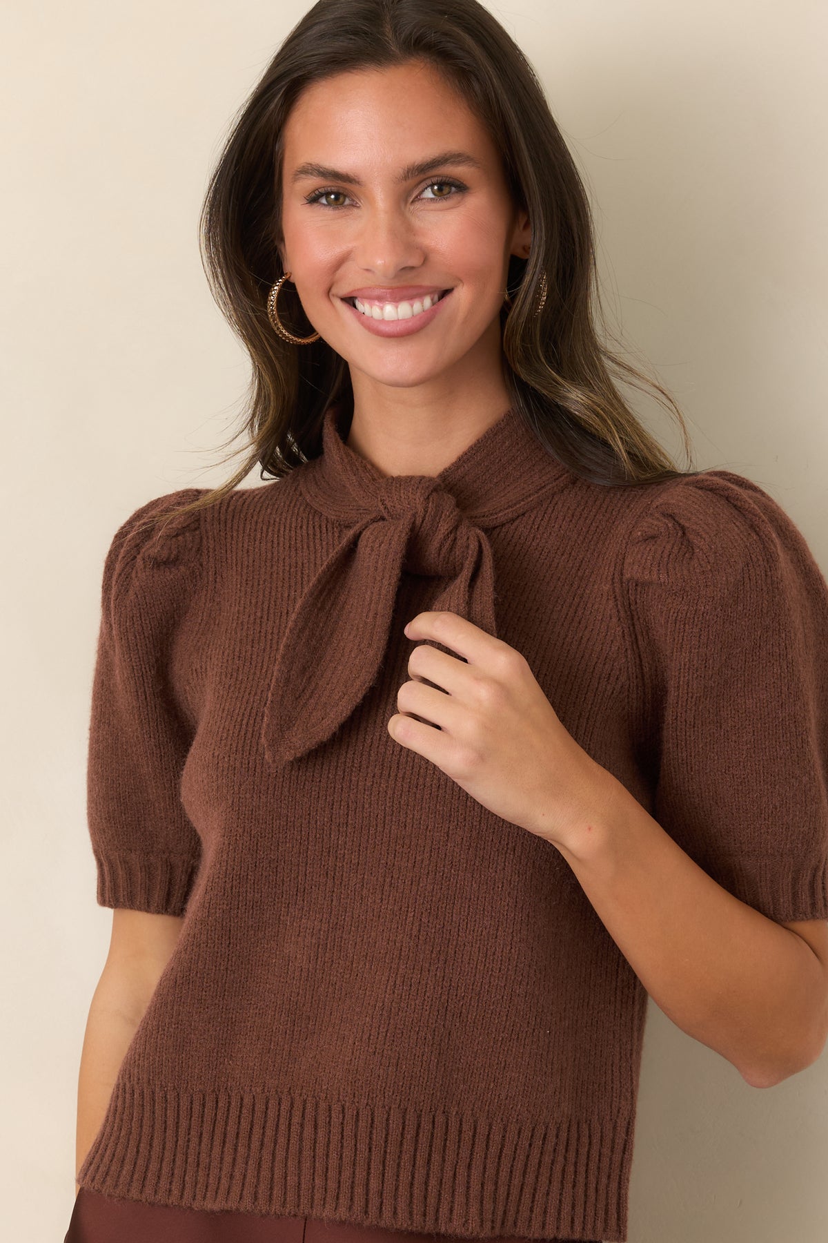 Close view of the ribbed knit top highlighting the oversized self-tie neckline and statement bow detail.
