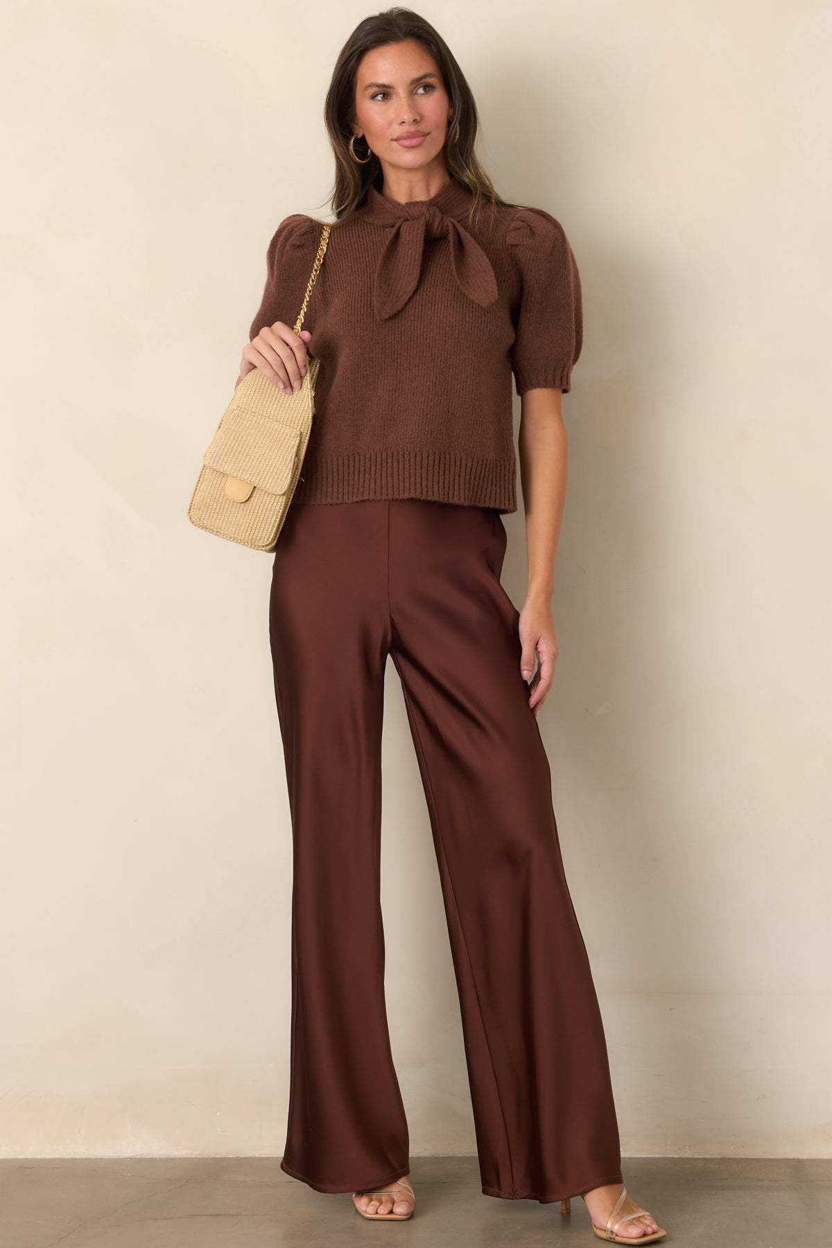 Ribbed knit top featuring an oversized self-tie neckline styled into a statement bow, puff sleeves, ribbed cuffs, and a fitted silhouette.