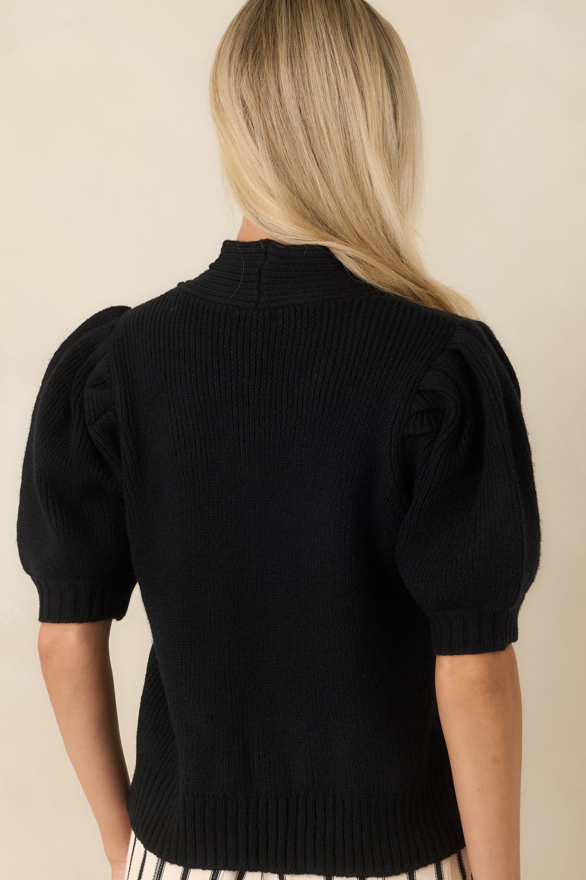 Back view of the ribbed sweater top featuring a fitted silhouette, long sleeves, and a clean ribbed hem.