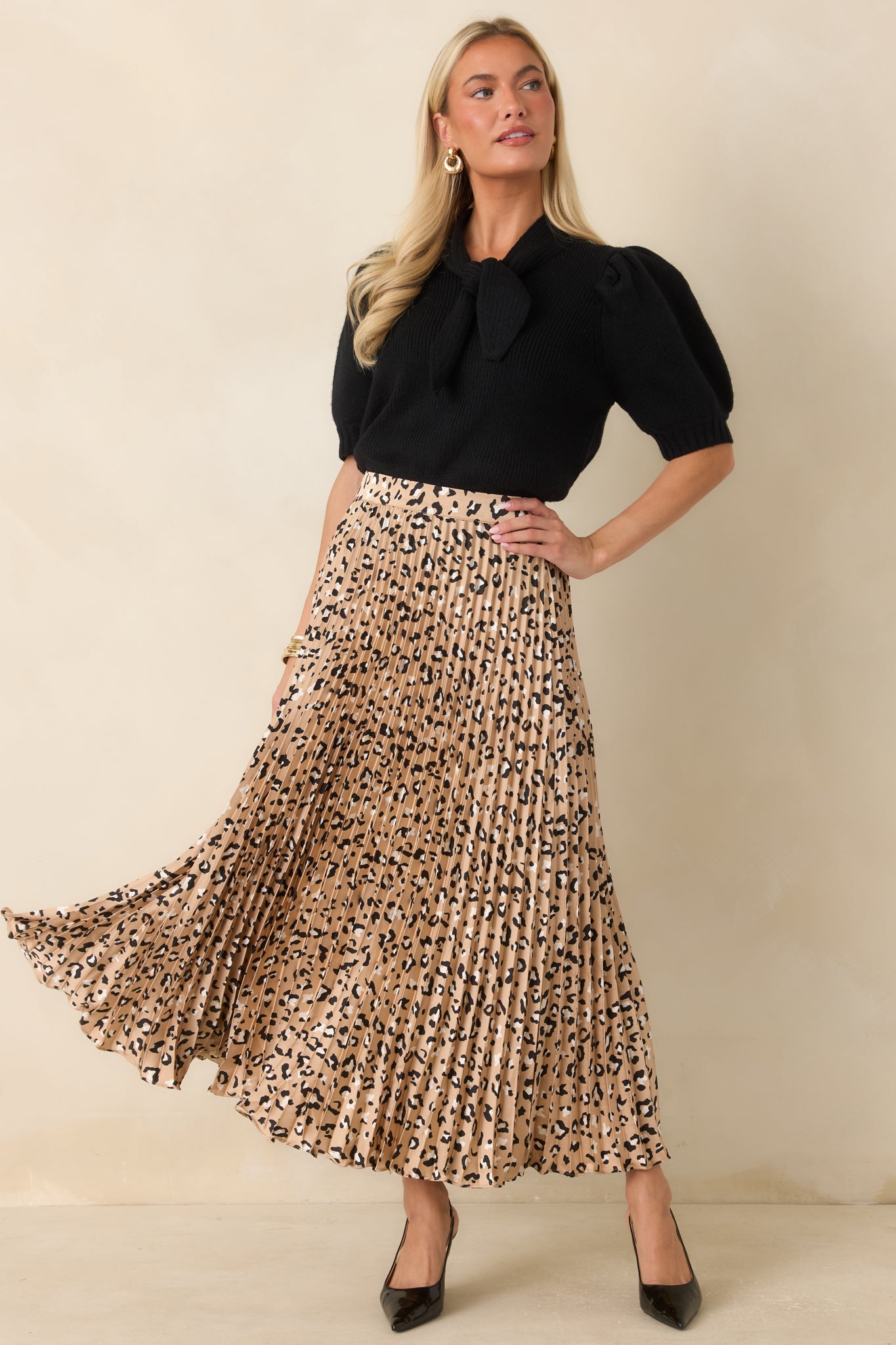 Ribbed sweater top featuring a feminine self-tie neckline, fitted silhouette, and puff sleeves that add a sophisticated touch to the timeless design.