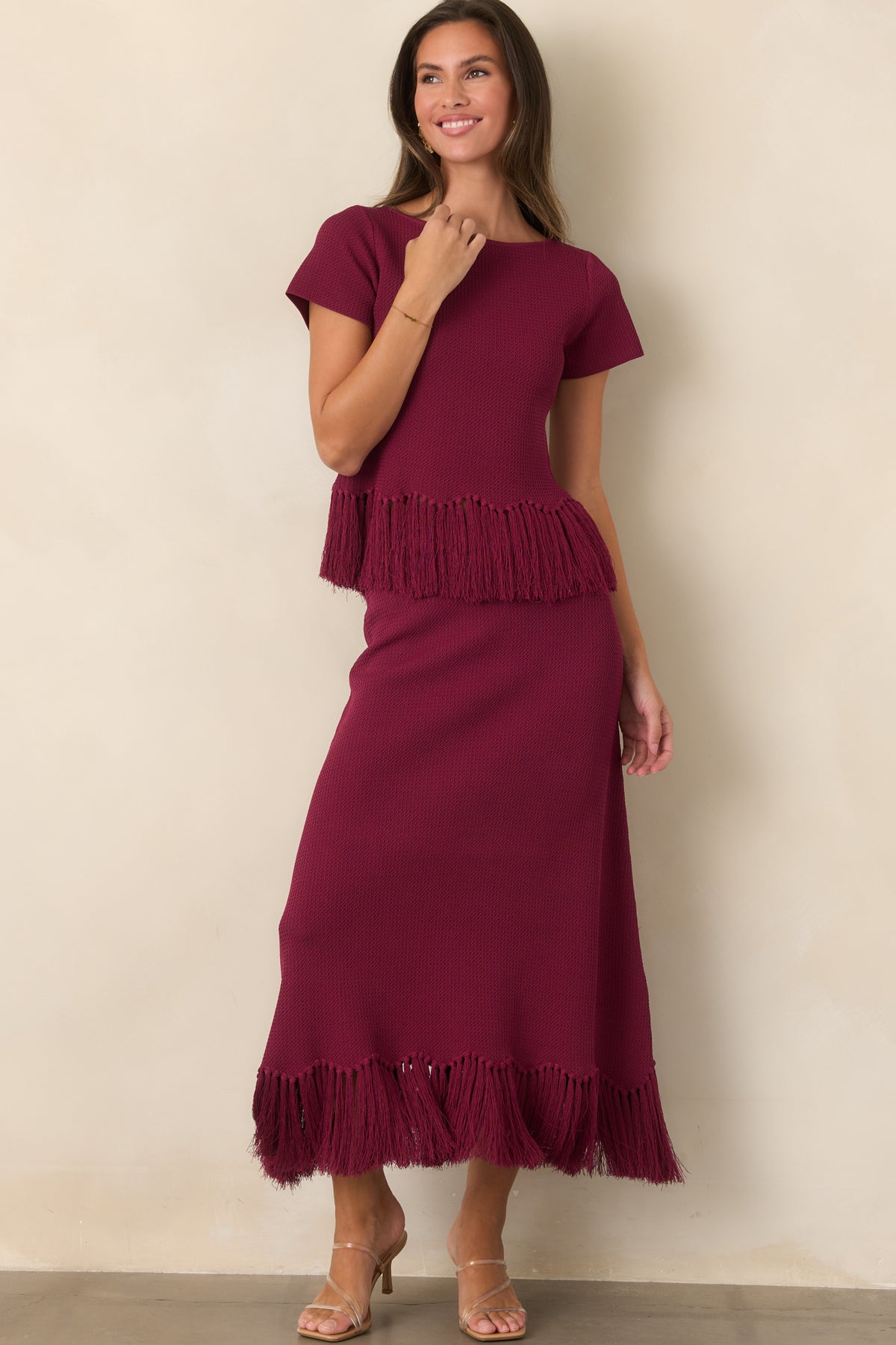 Rich berry textured knit top featuring a boat neckline, short sleeves, and fringe-trimmed hem.