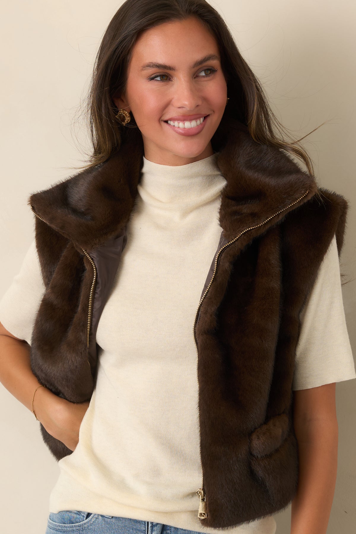 Rich brown faux fur surrounds the wide collar and clean zip-front design of the vest.