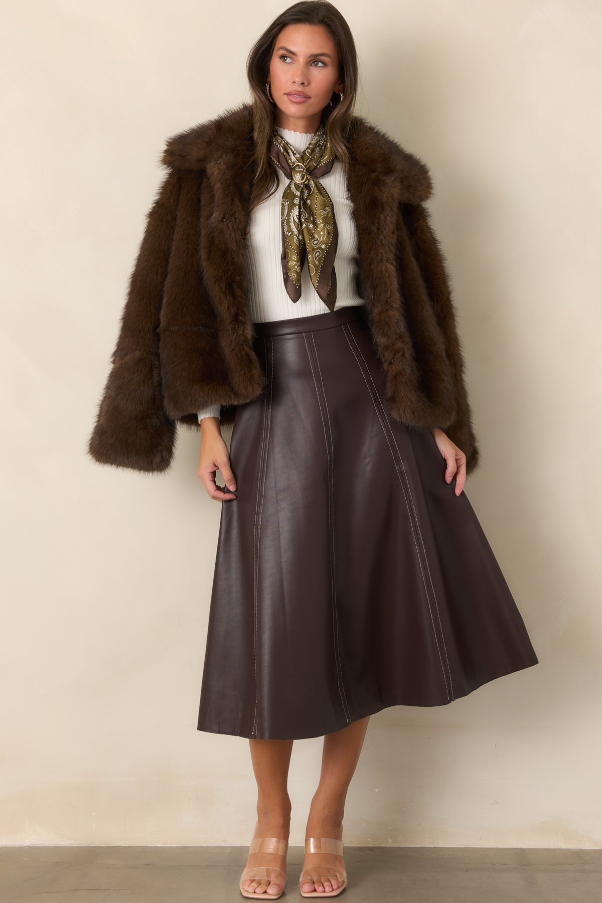 Rich brown skirt highlighting the smooth faux leather finish, defined waist, and dimensional paneled design.