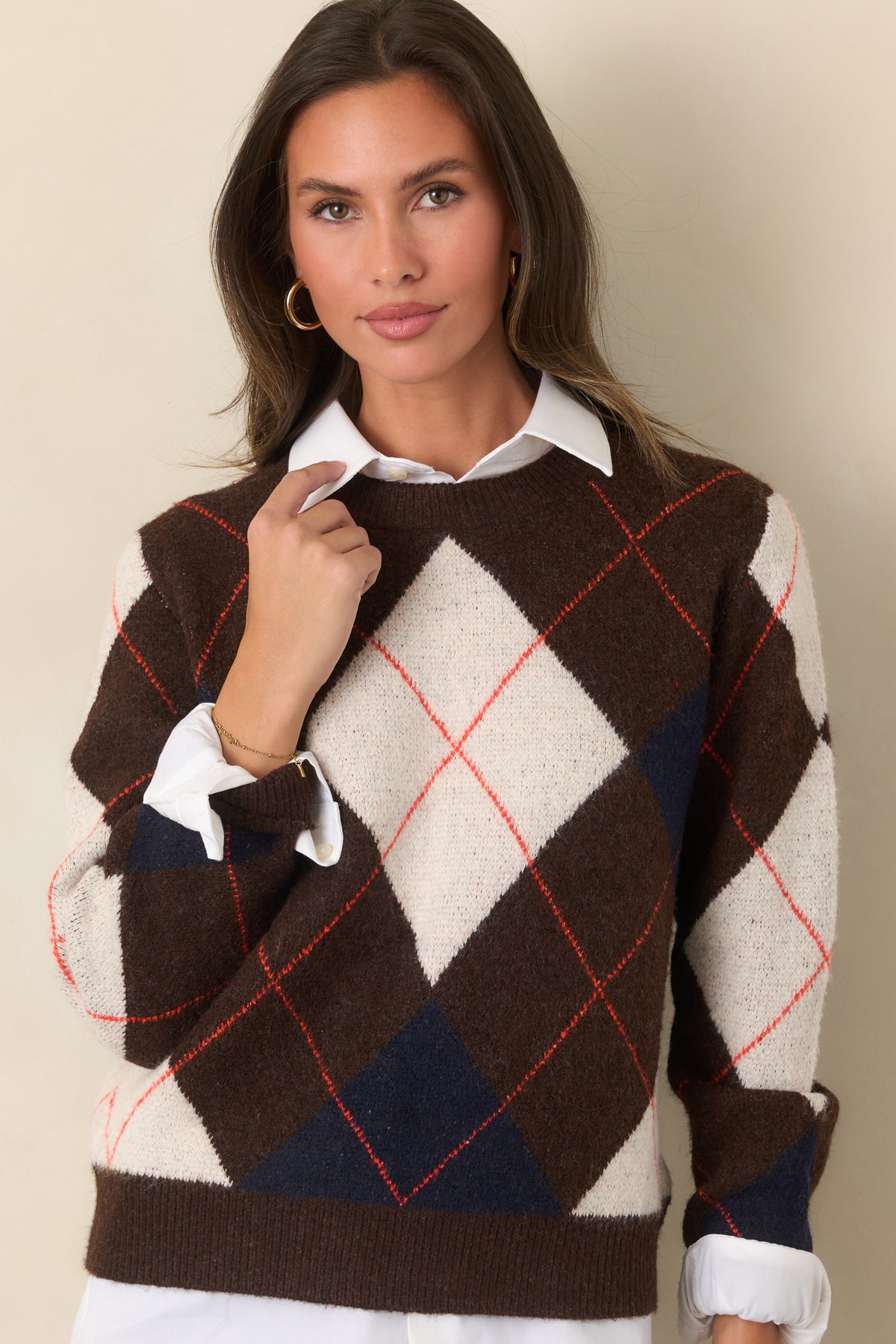 Rich brown sweater top accented with geometric ivory and navy diamonds, fine rust-red striping, and ribbed trim at the neckline and hem.
