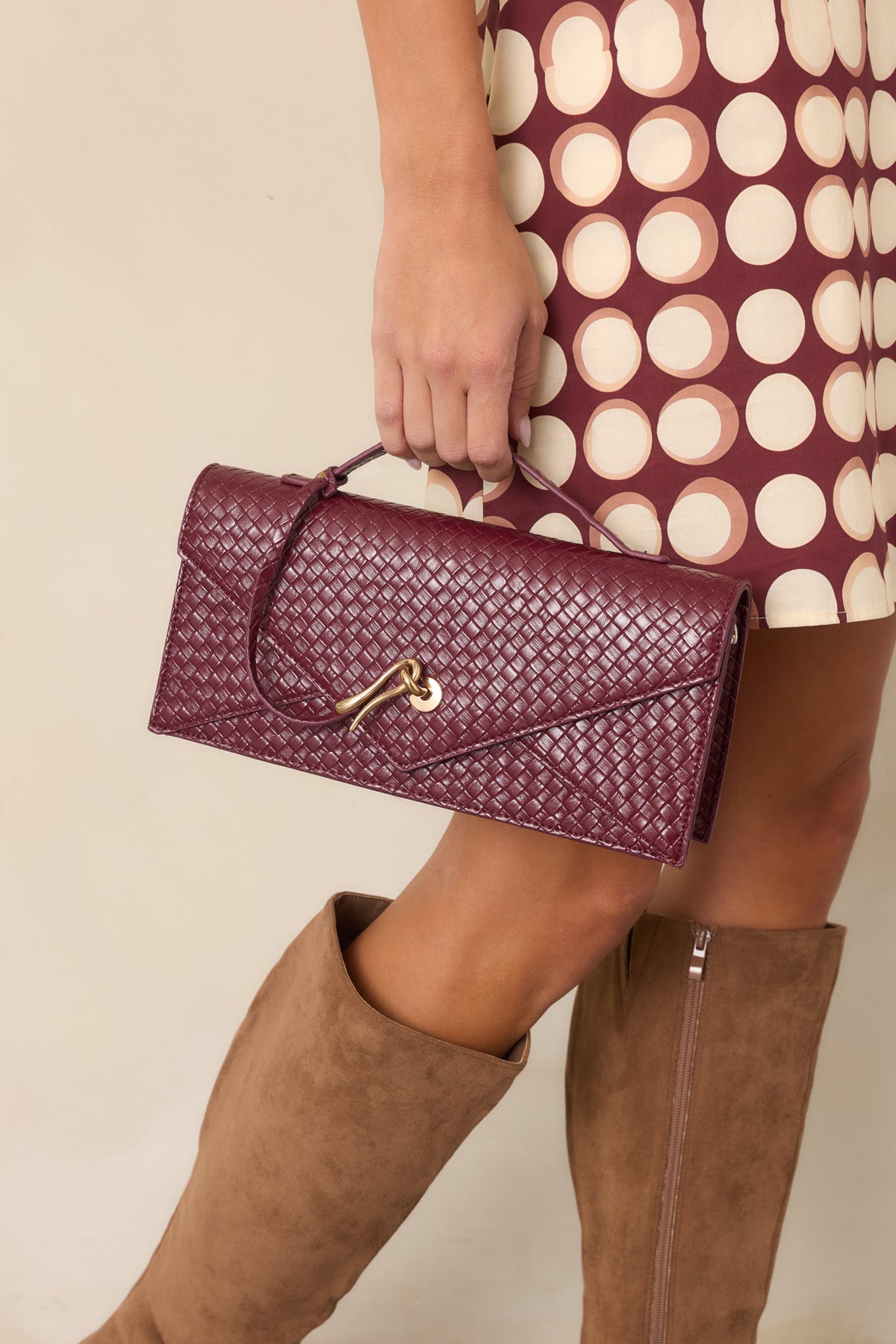 Rich burgundy clutch featuring the pointed flap and sculptural gold-tone hardware.