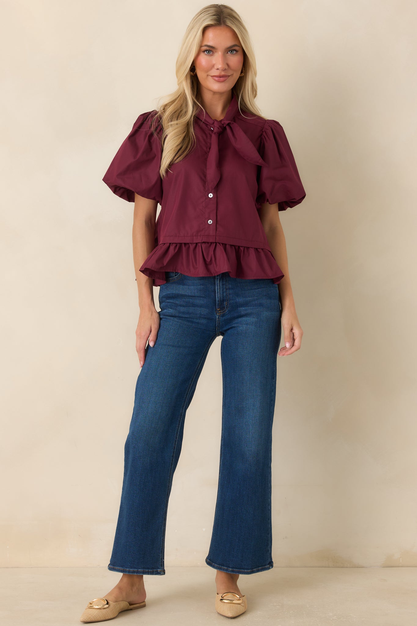 Rich wine blouse designed with oversized puff sleeves, a dramatic bow neckline, and a flattering peplum silhouette.
