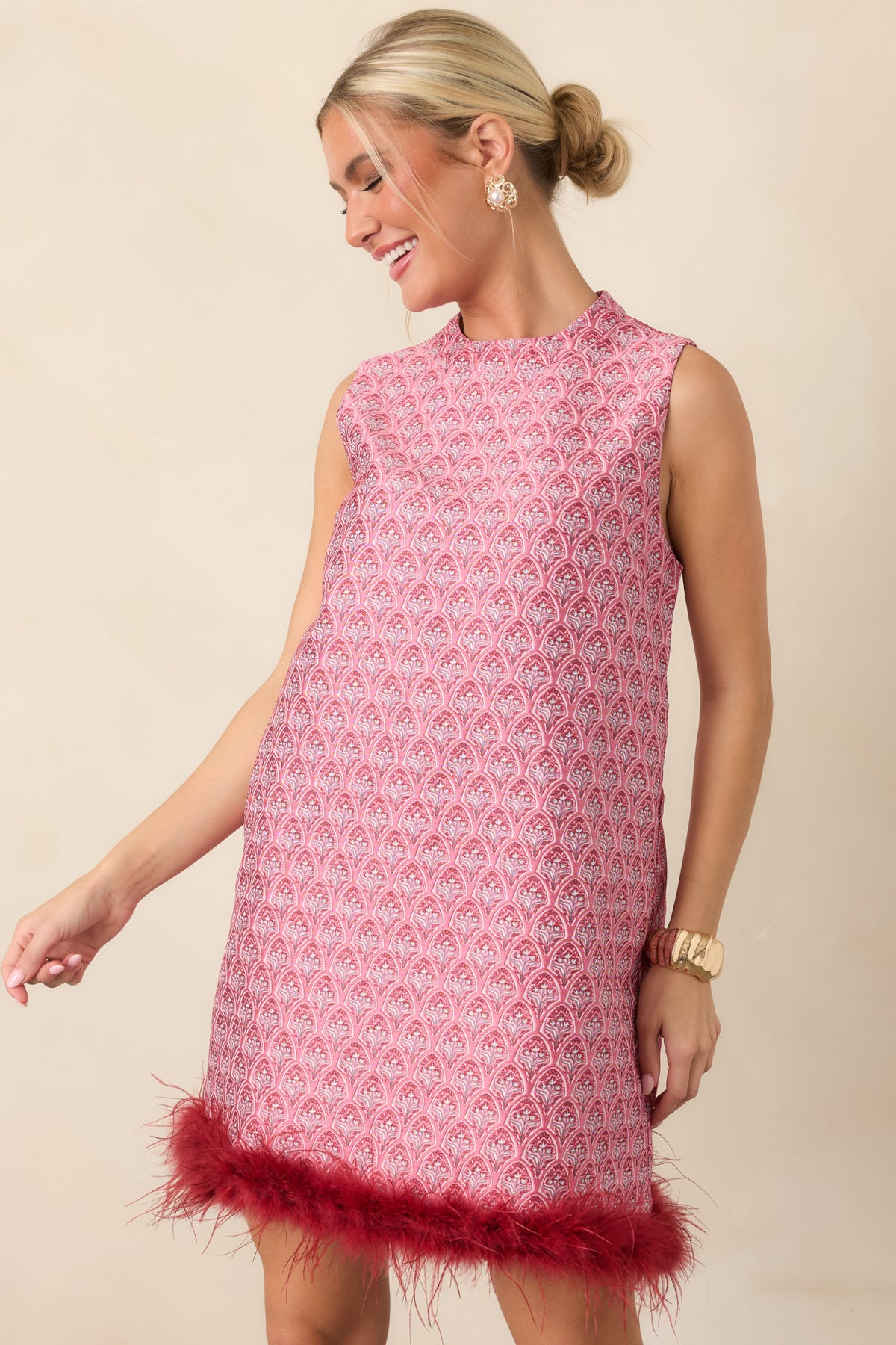 Ornate rose pink and burgundy floral pattern decorates the sleeveless shift dress with a feather-trimmed hem.