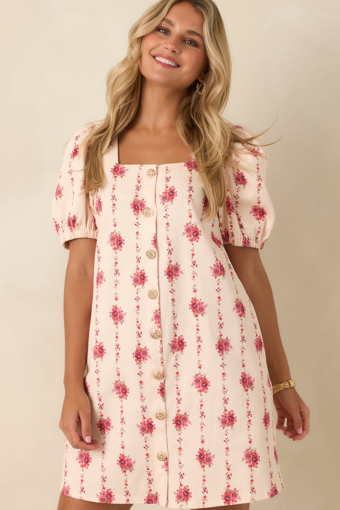 Rose print mini dress featuring softly puffed sleeves, structured fabric, square neckline, and gold-tone detailing.