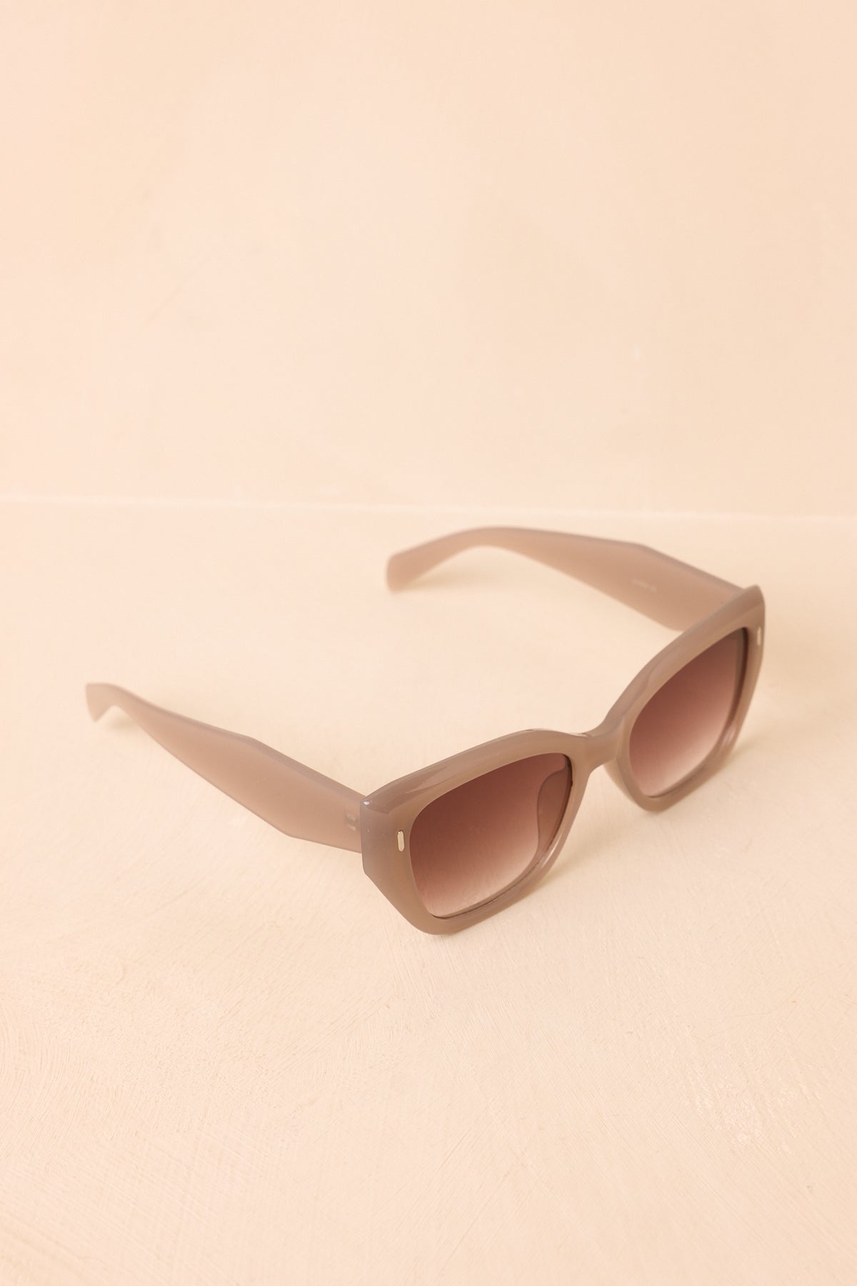 Rosy taupe sunglasses featuring glossy frames and subtly lifted cat-eye corners.
