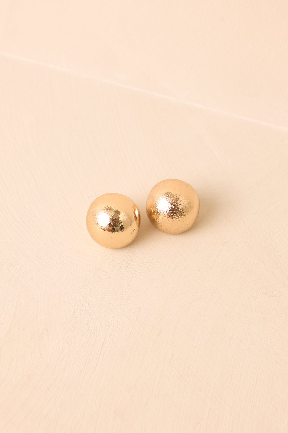 Round gold-tone earrings featuring a clean sculptural form and subtle surface texture.
