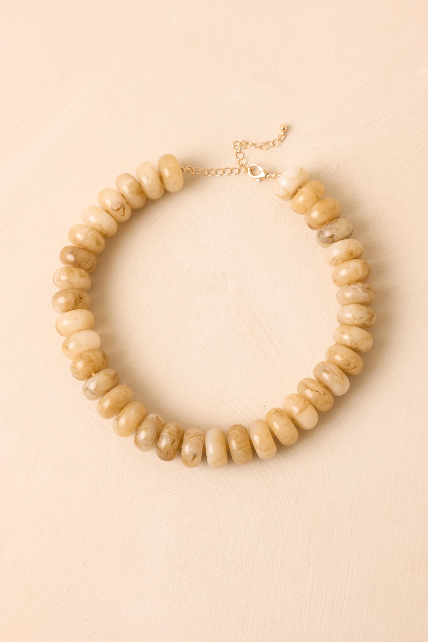 Rounded necklace displayed against a beige background, showcasing its sculptural silhouette and timeless appeal.
