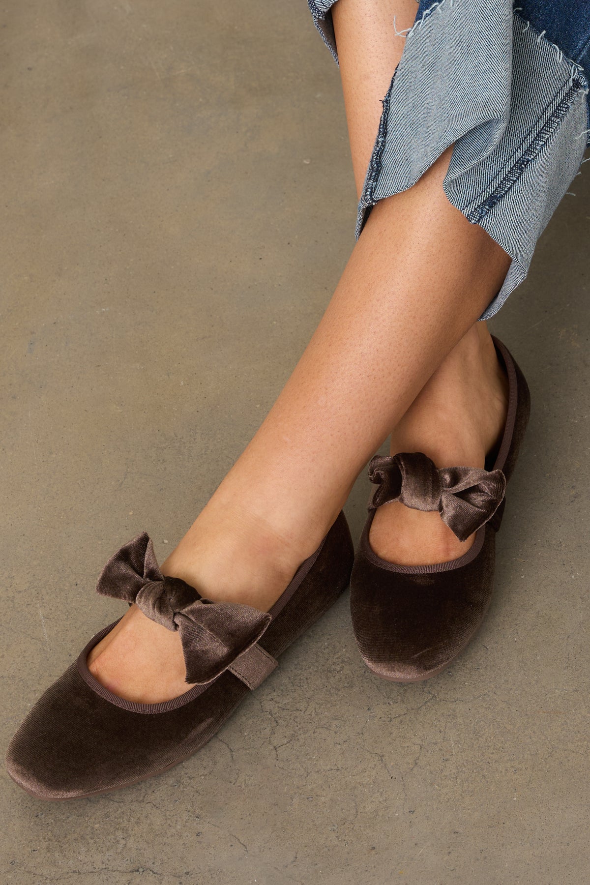 Rounded-toe brown velvet flats feature a decorative bow on the strap and a classic low heel.