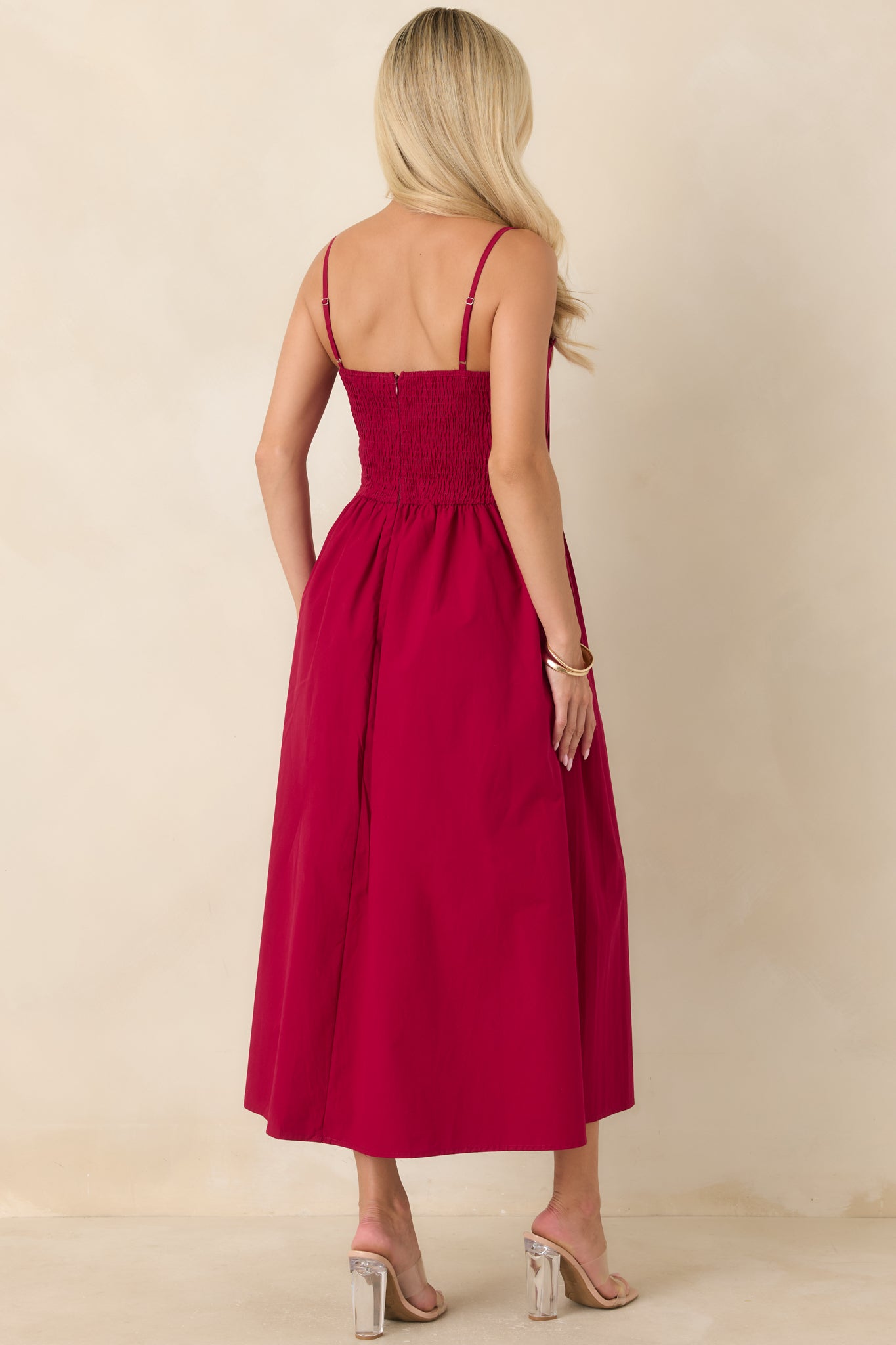 Rear view of the ruby red cotton midi dress showcasing the comfortable smocked back, adjustable spaghetti straps, gathered waist, and flowing full skirt.