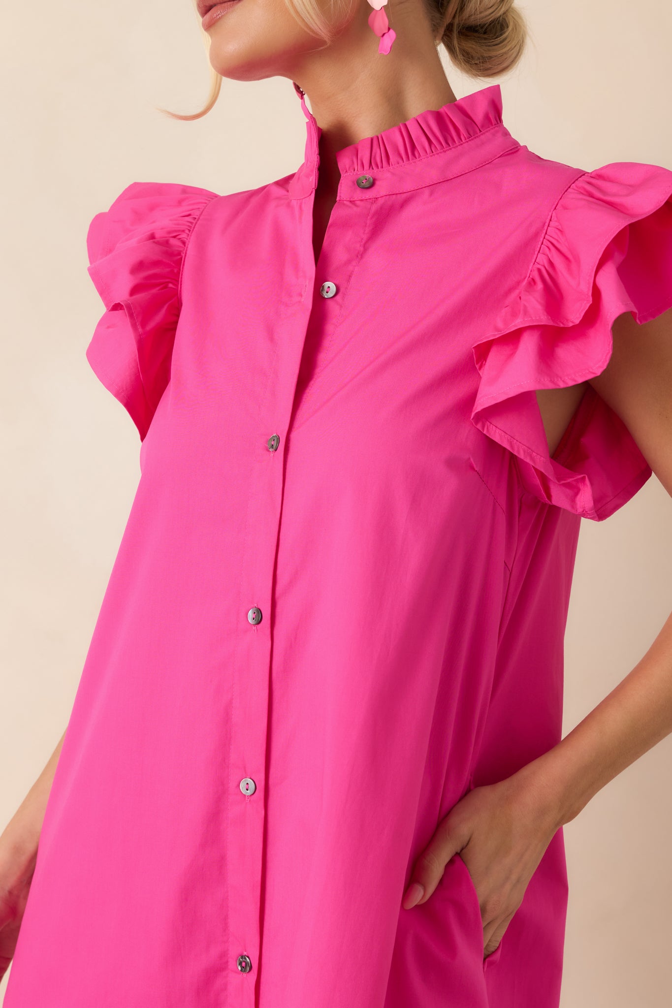 Detailed view of the ruffle-trimmed collar, button-front placket, and flutter sleeve construction on the cotton dress.