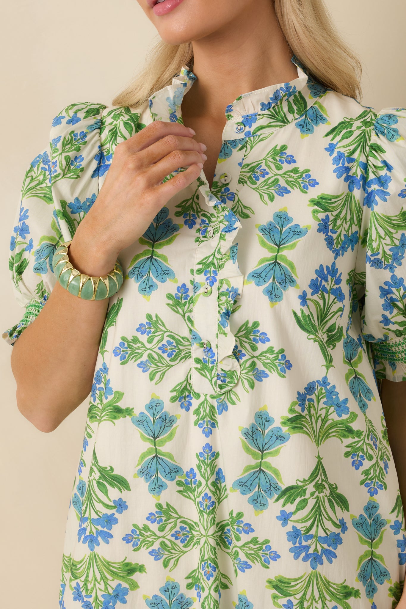 Detailed view of the ruffle-trimmed neckline, floral print, and soft cotton texture with elastic sleeve cuffs.