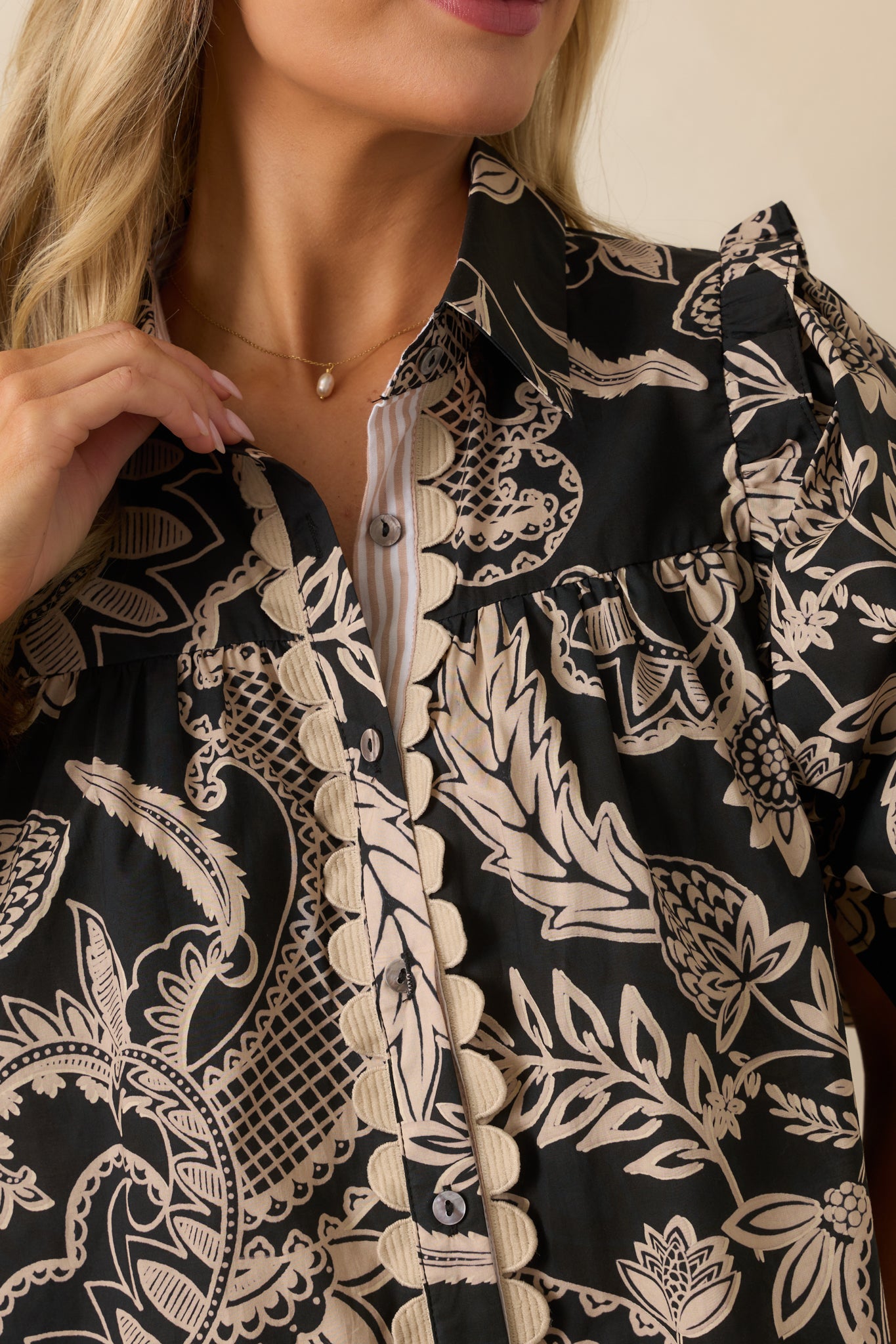 Zoomed-in view of the ruffle trim, puff sleeve gathering, and black and beige floral cotton fabric.