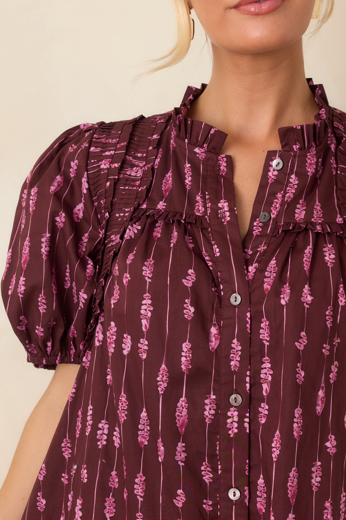 Close-up of the ruffled split neckline and pintucked shoulder detailing on the cotton striped dress.