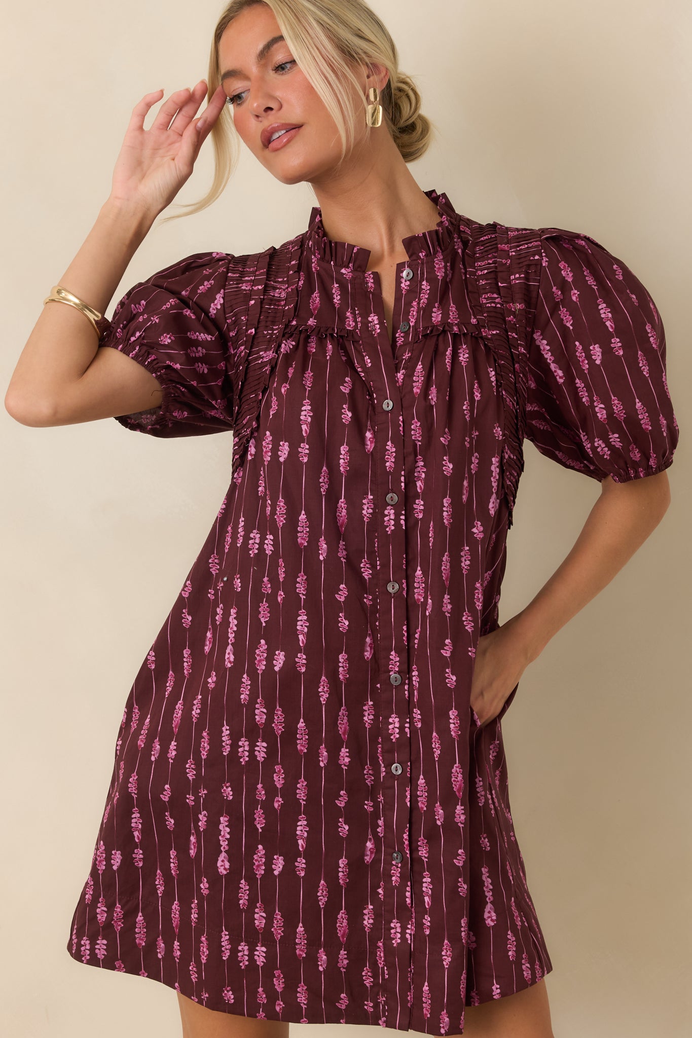 Close view of the mini dress highlighting the ruffled split neckline, button-front design, and vertical stripe pattern.