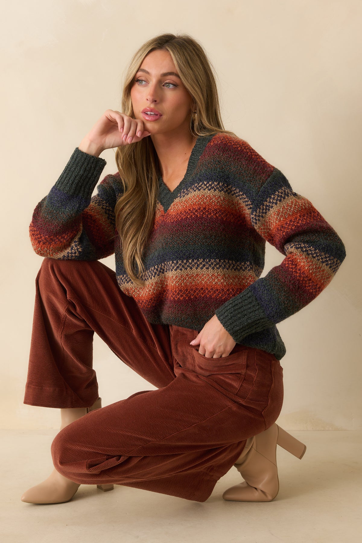 Front-focused view showing ribbed V-neck and multicolor stripe detail on rust knit sweater.