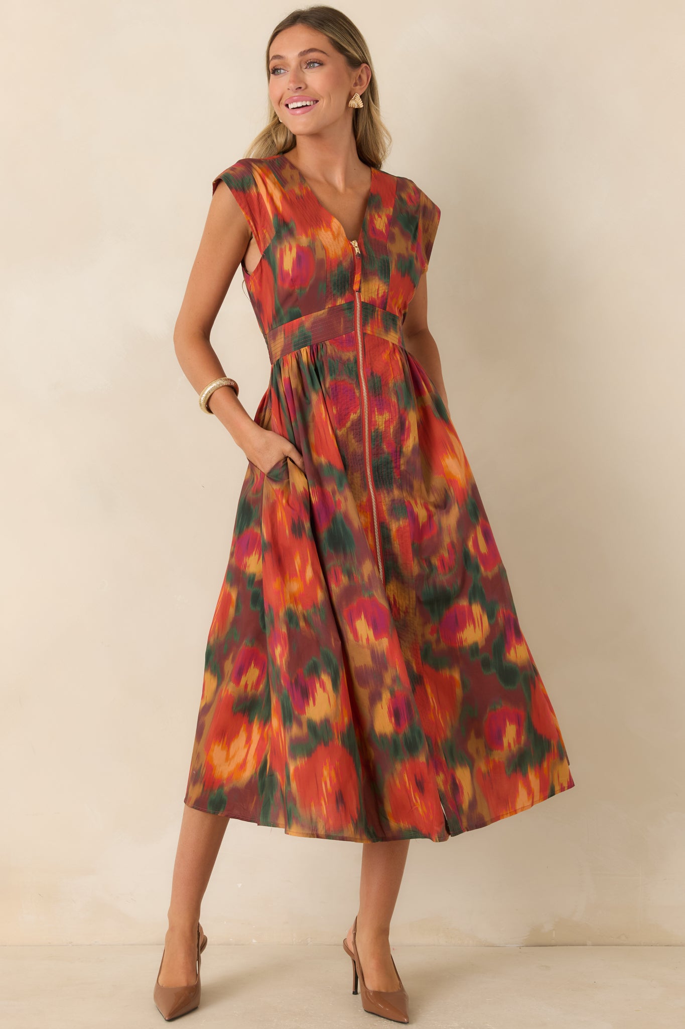 Rust-toned cotton dress featuring an artistic floral pattern, fitted bodice, gathered midi skirt, and polished gold-tone front zipper.