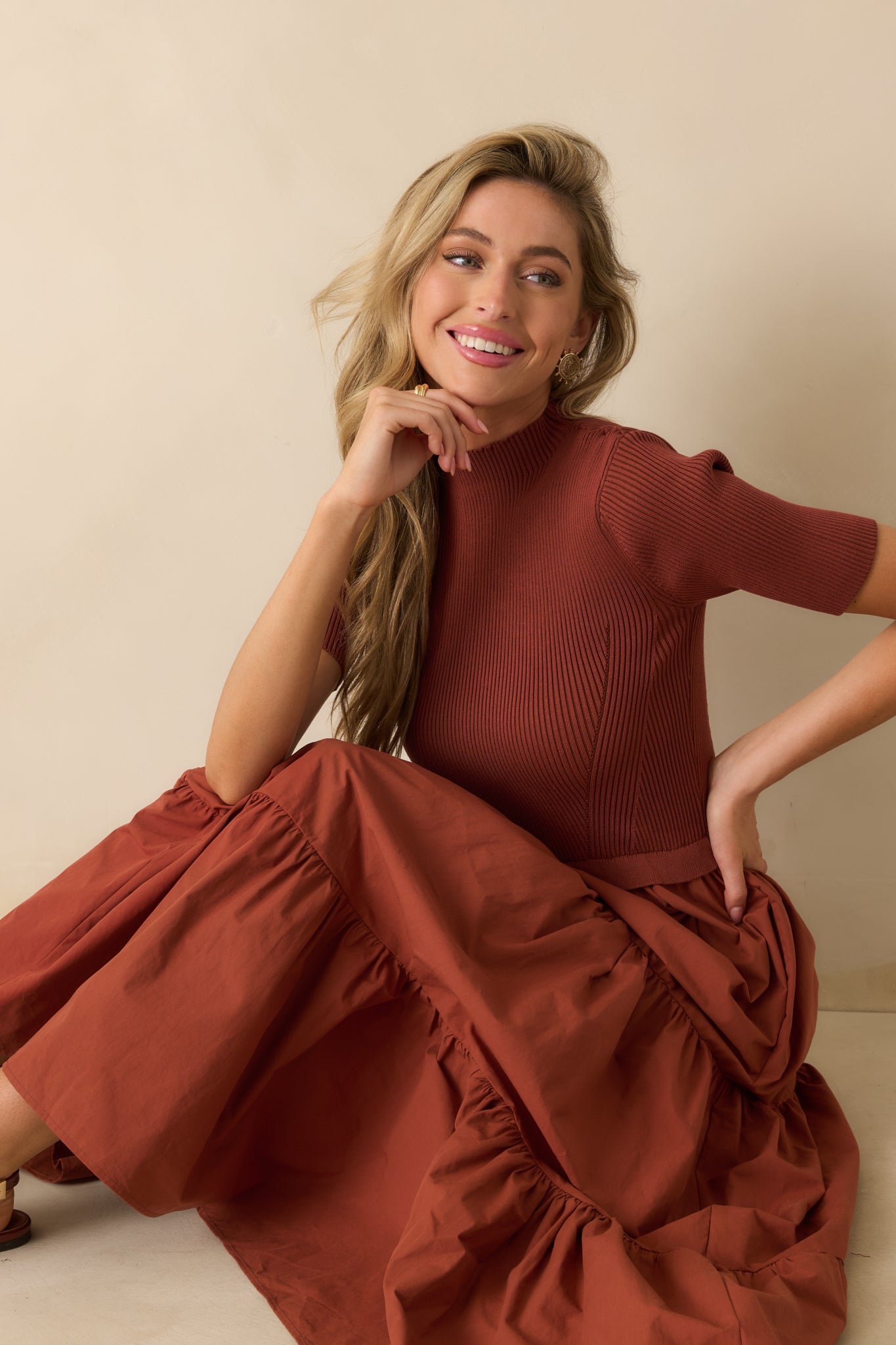 Rust red maxi dress with a ribbed knit top and flowing tiered skirt, styled with a relaxed yet polished silhouette.