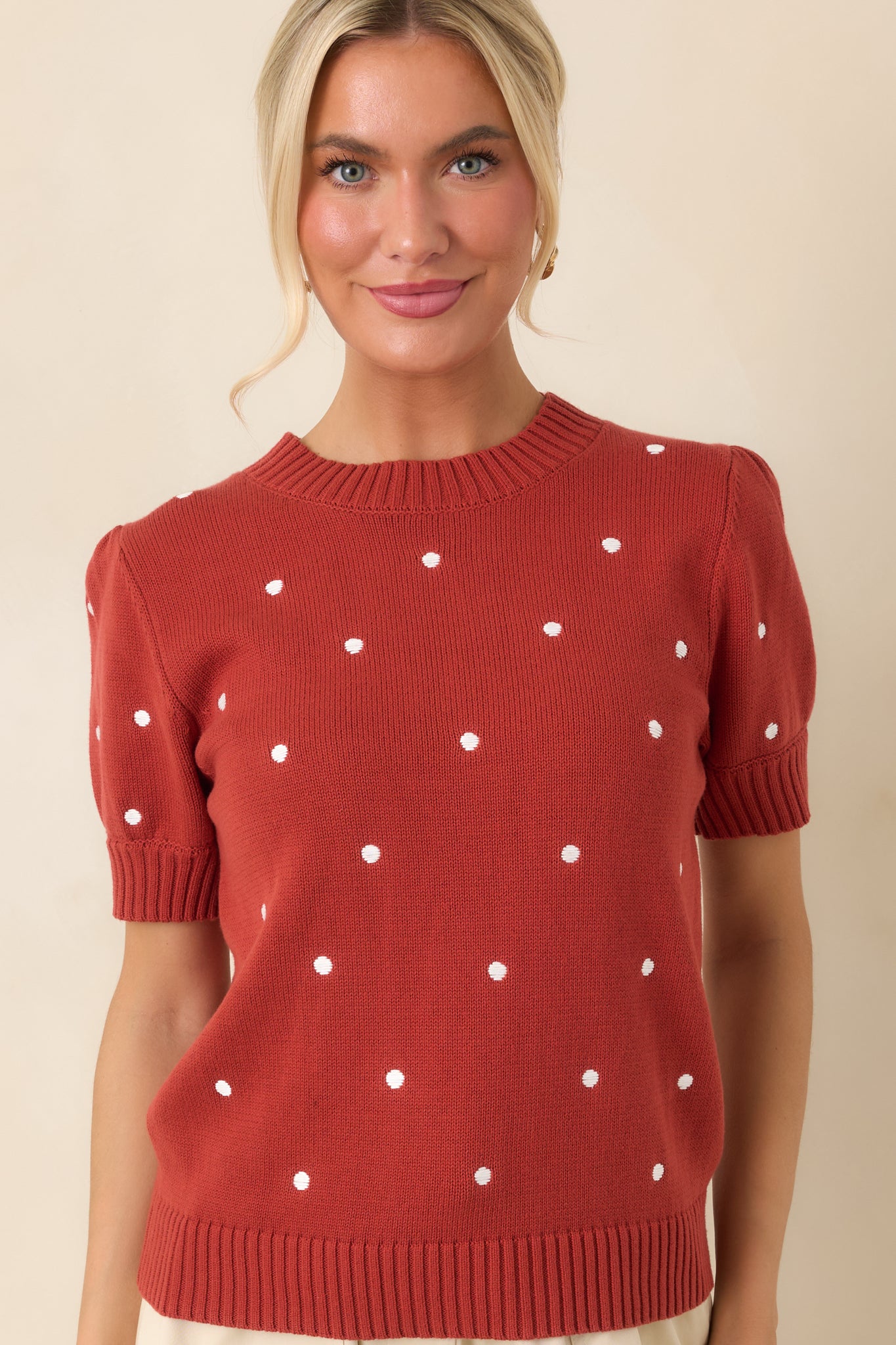 Rust red polka dot top showcasing the ribbed neckline, smooth knit construction, and softly structured silhouette.