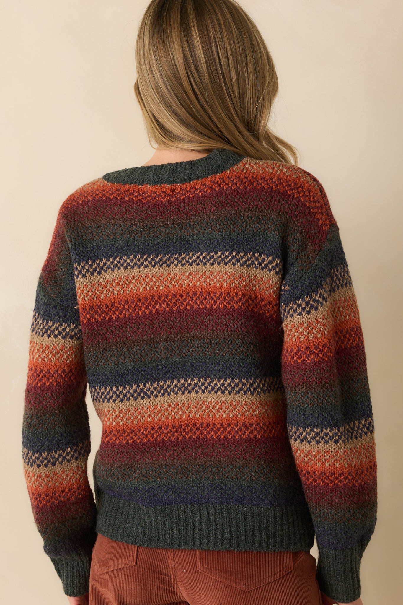 Rear view of rust striped sweater revealing full stripe pattern, ribbed hem, and relaxed silhouette.