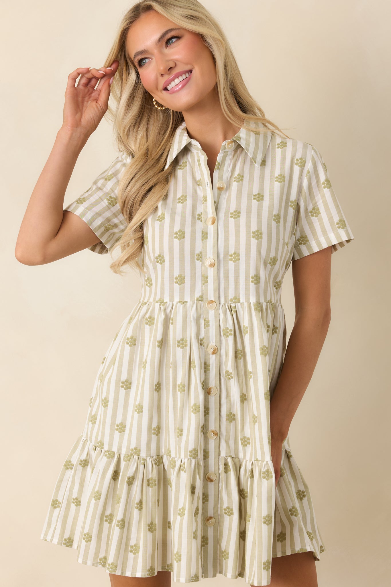 Close view of sage green cotton dress featuring intricate floral embroidery, short sleeves, and classic button-front detailing.