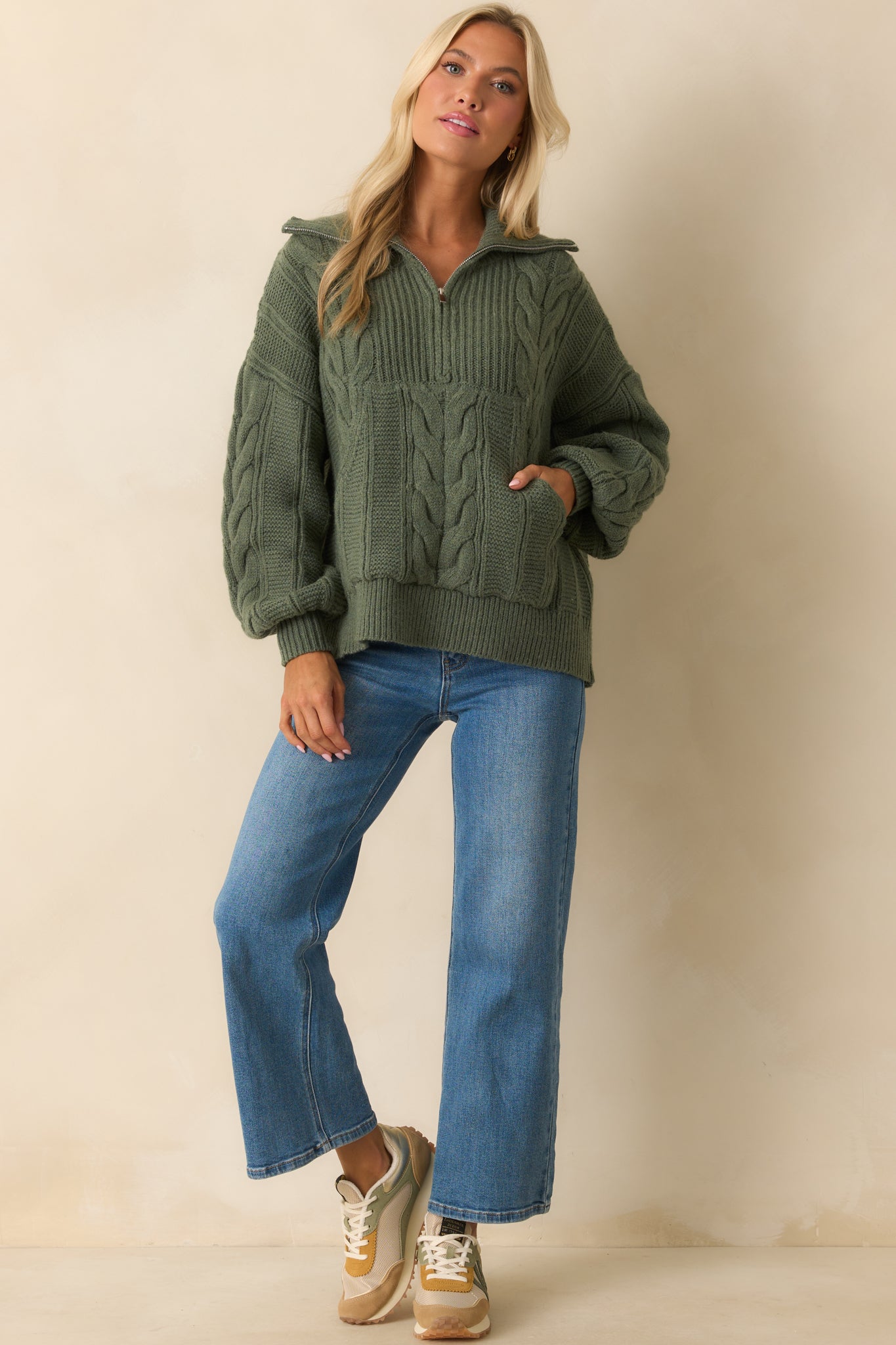 A front view of the sage green cable knit sweater with a fold-over collar, quarter zip, and relaxed fit.