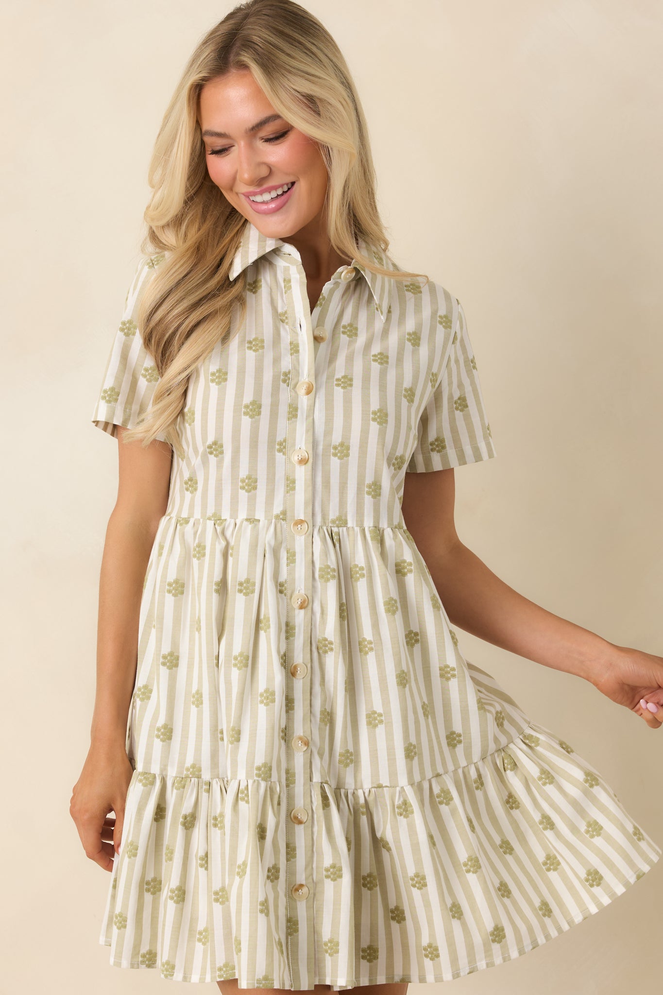 Sage green mini dress detail highlighting embroidered floral patterns, button front closure, and the structured collared neckline.