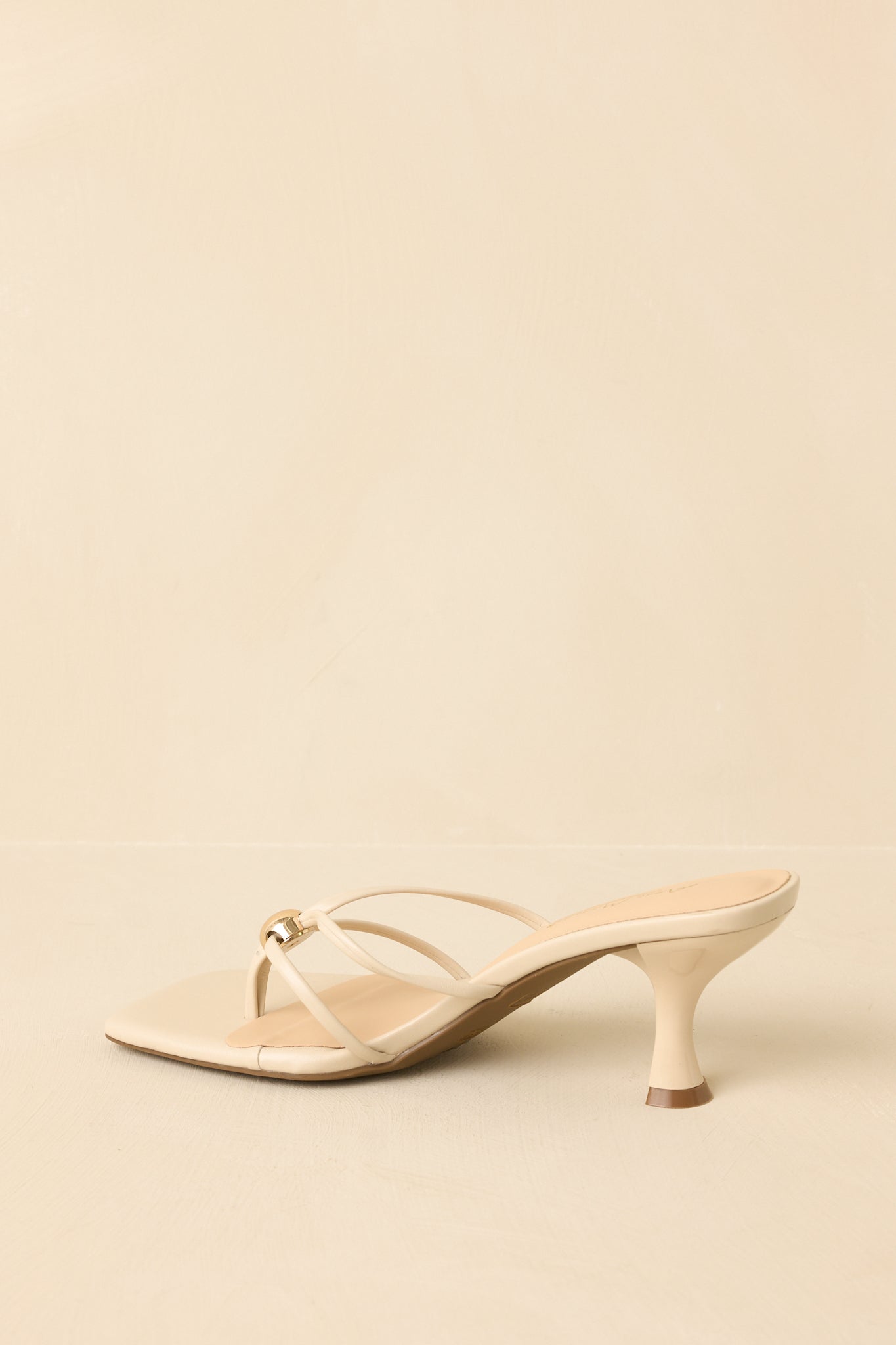 Natural faux leather sandals angled to emphasize the lightweight, elegant kitten heel shape.