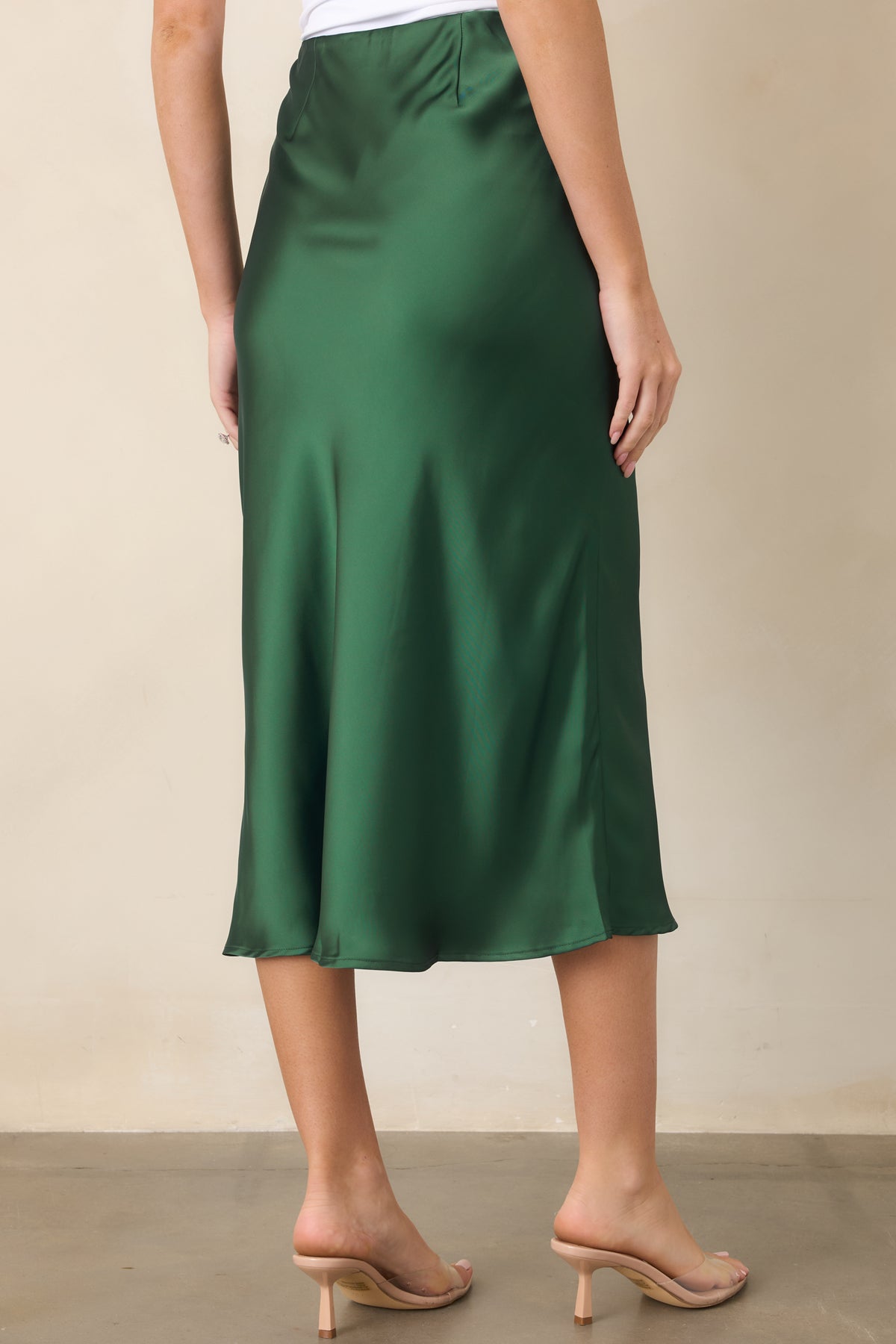 Rear view of the sleek satin midi skirt showcasing its elastic waistband, smooth hip-skimming fit, and graceful flared hem.
