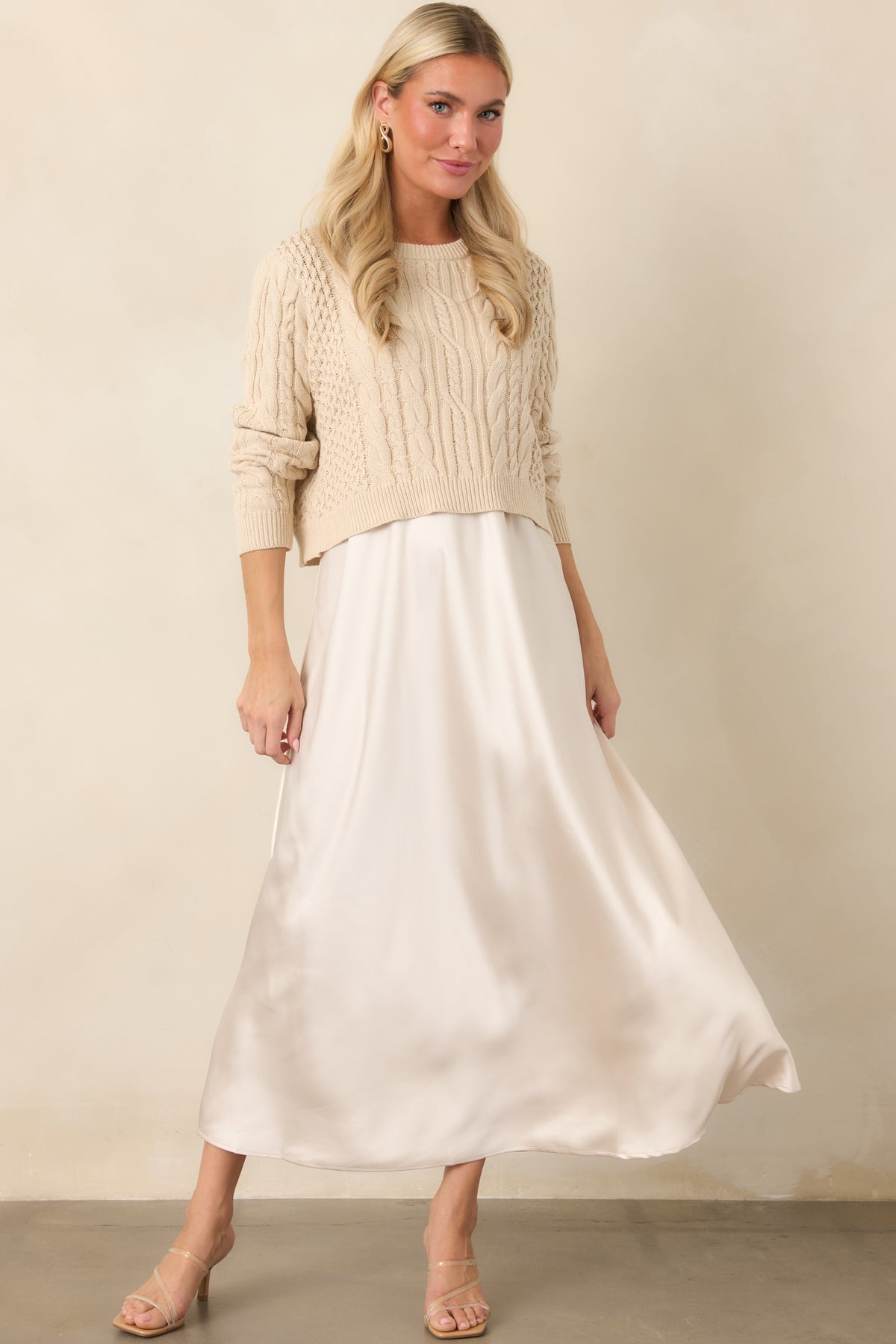 Satin maxi dress showcasing its flowing A-line shape beneath a cropped sweater with mixed cable-knit detailing.
