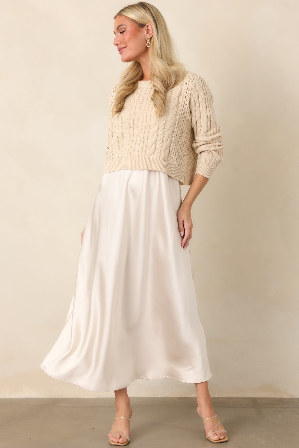 Fluid satin maxi dress featuring a softly draped A-line silhouette layered with a textured cropped cable-knit sweater.